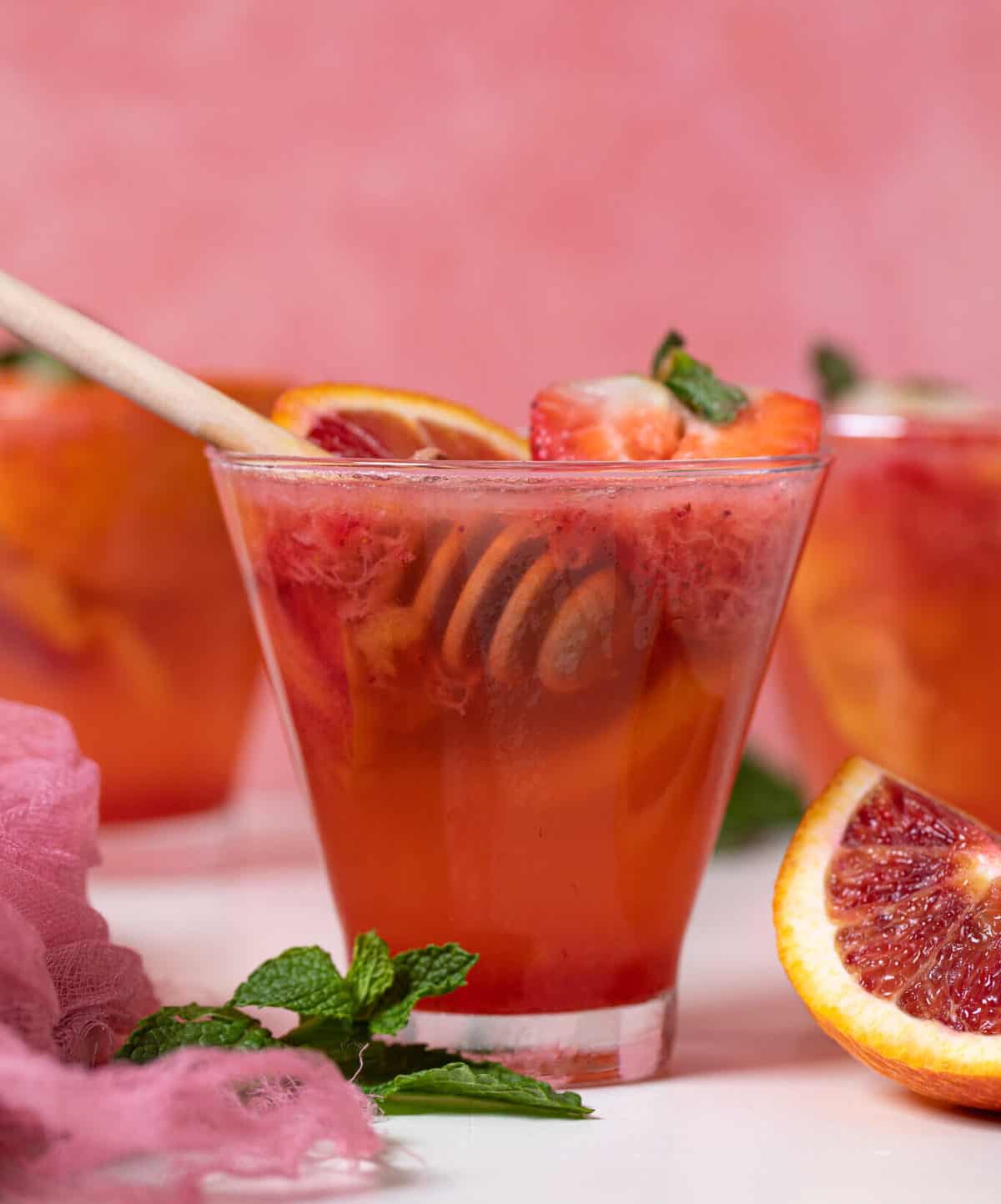 Blood Orange Strawberry Mocktail in a glass with a honey dipper