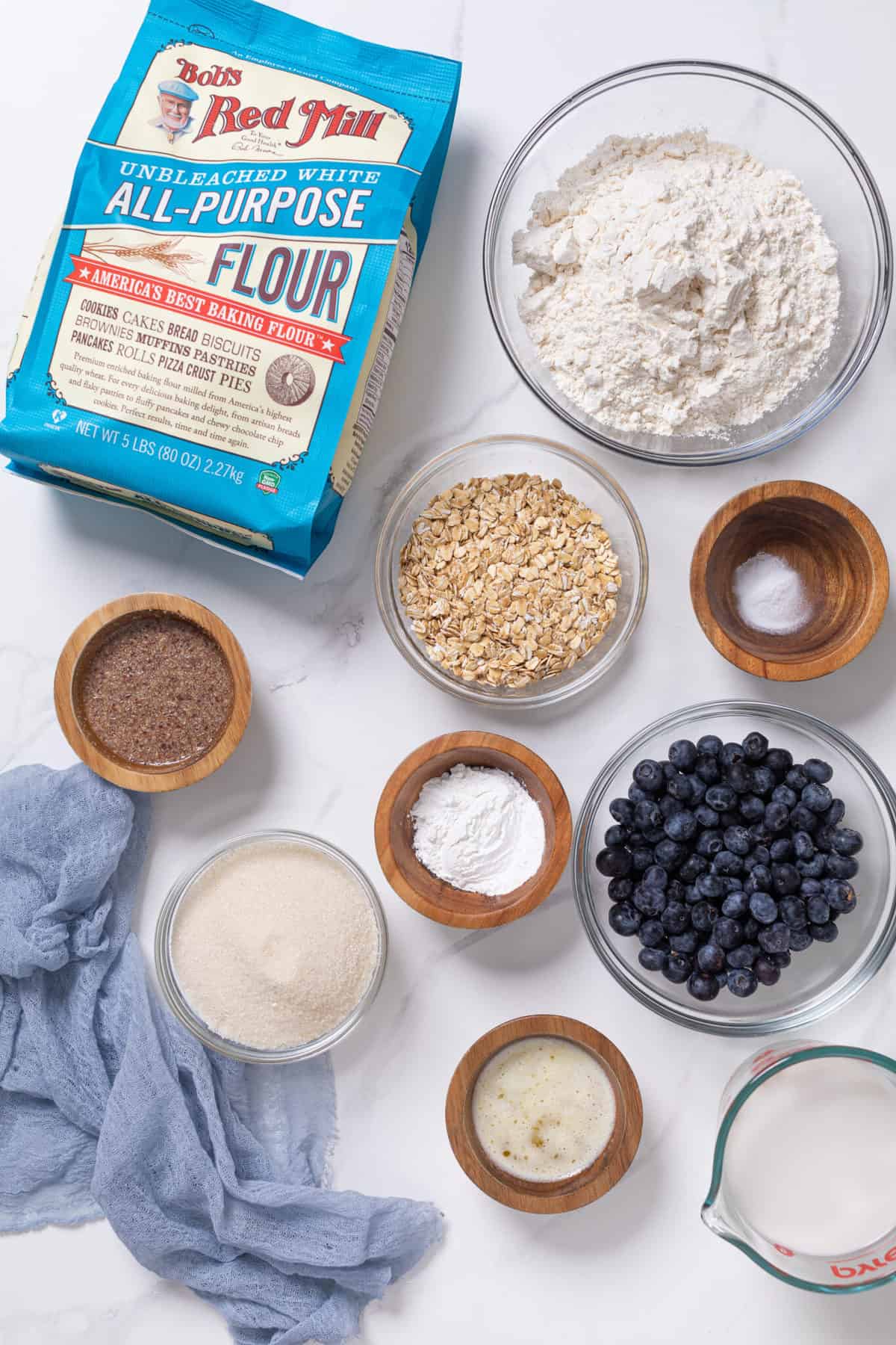Bowls of ingredients on a table including oats, blueberries, and Bob\'s Red Mill flour.