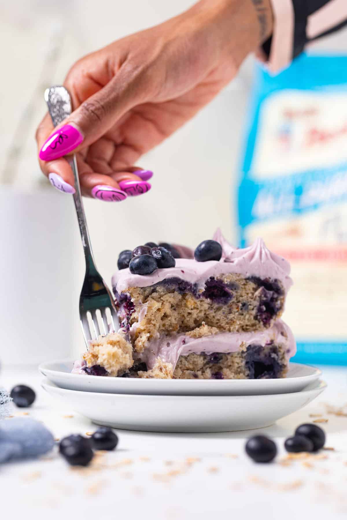 Fork taking a bite from a slice of Blueberry Oatmeal Cake with Cream Cheese Frosting.