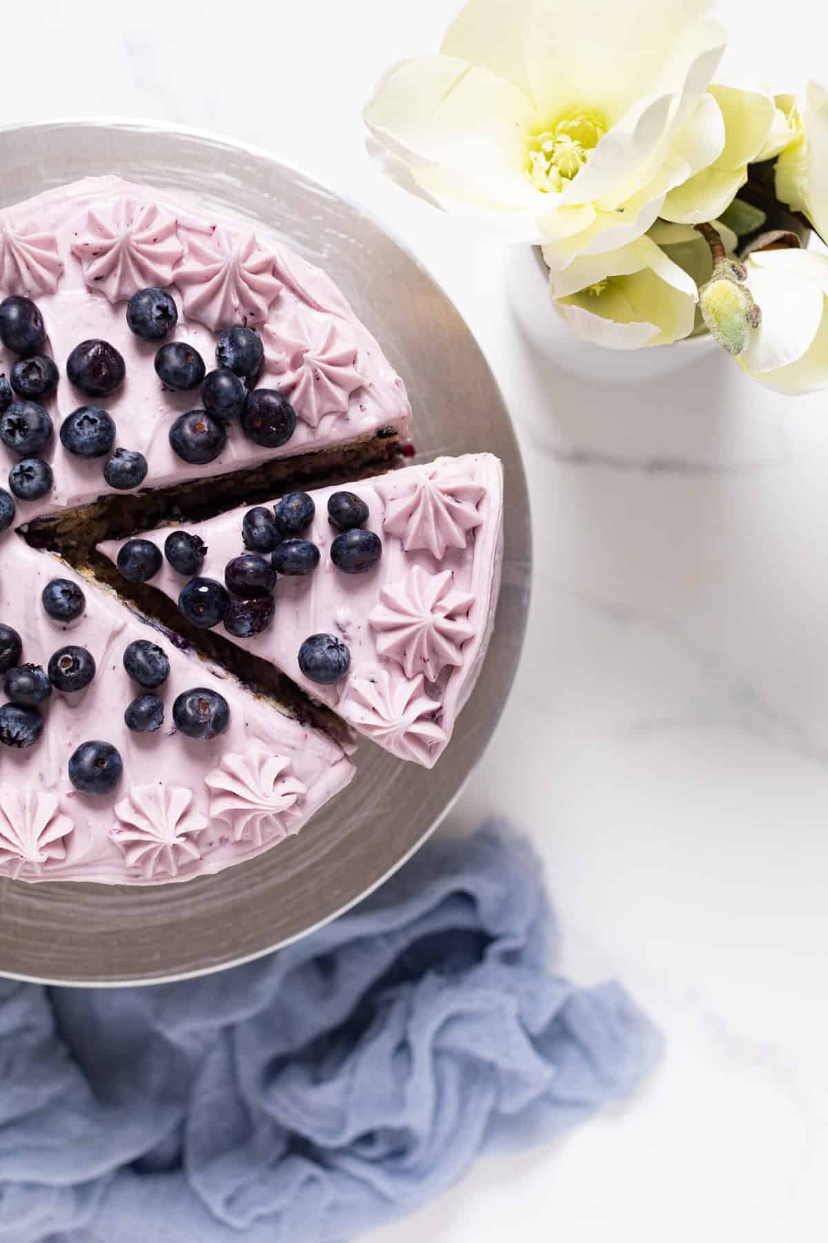 Sliced Blueberry Oatmeal Cake with Cream Cheese Frosting topped with blueberries.