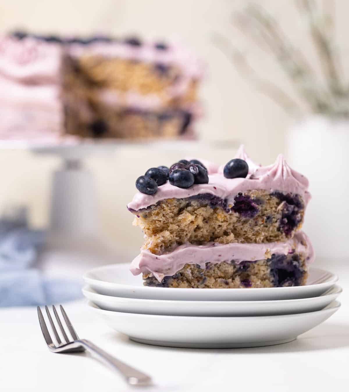 Blueberry Oatmeal Cake with Cream Cheese Frosting on three stacked plates.