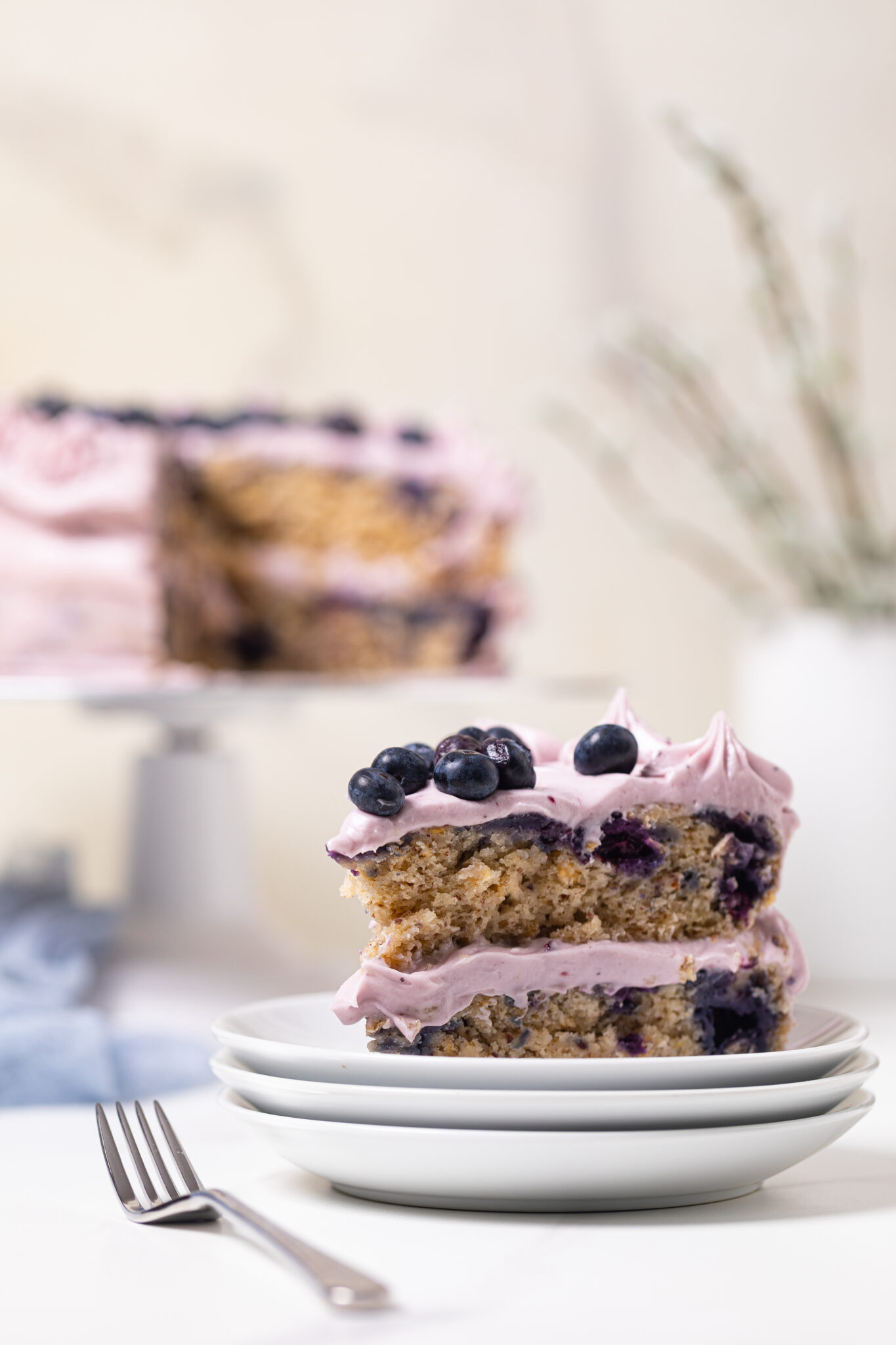 Slice of Blueberry Oatmeal Cake with Cream Cheese Frosting topped with blueberries.