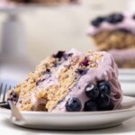 Slice of Blueberry Oatmeal Cake with Cream Cheese Frosting lying down on a small plate.