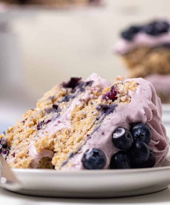 Slice of Blueberry Oatmeal Cake with Cream Cheese Frosting lying down on a small plate.