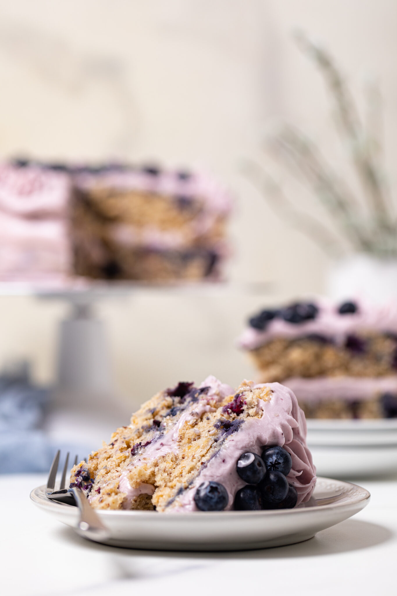 Slice of Blueberry Oatmeal Cake with Cream Cheese Frosting lying down on a small plate.