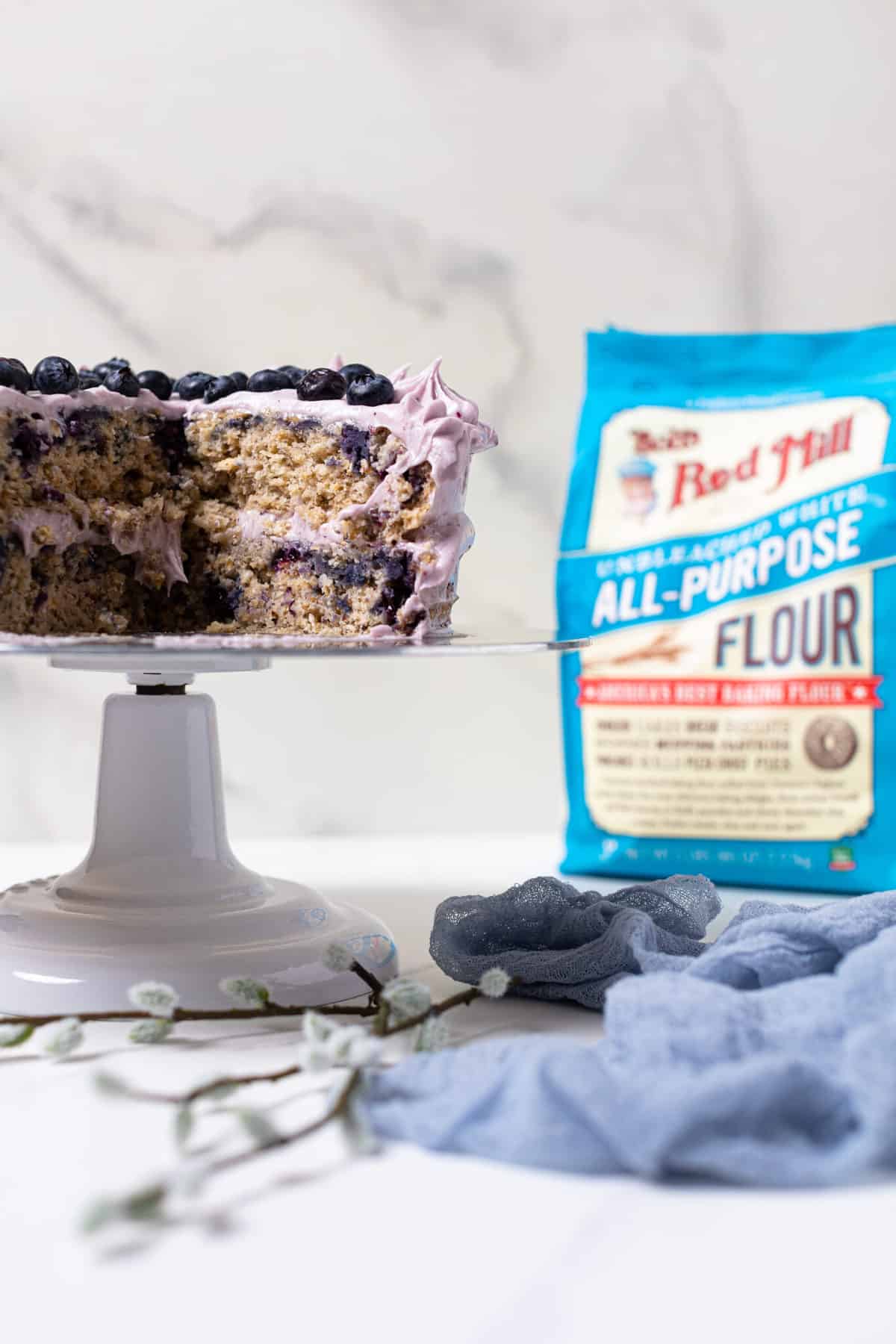 Blueberry Oatmeal Cake with Cream Cheese Frosting in front of a bag of Bob\'s Red Mill flour.