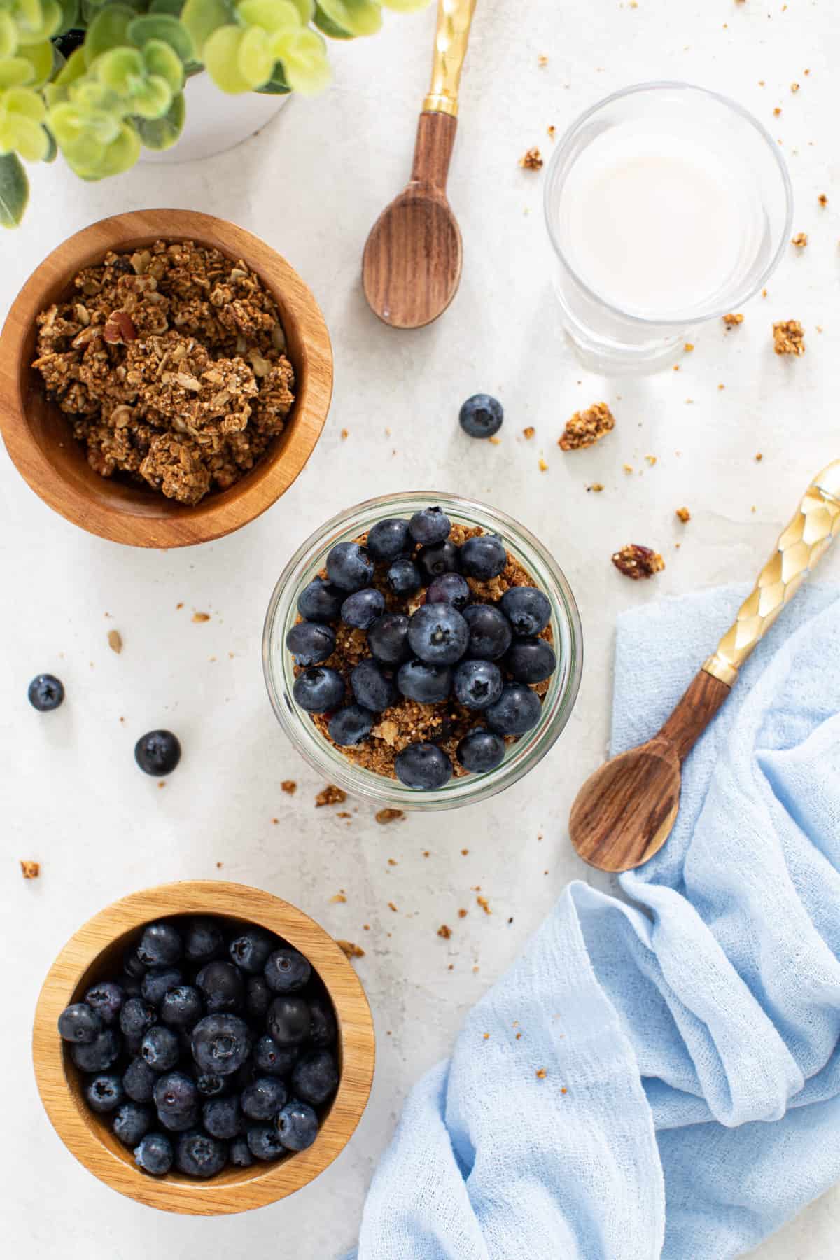 overhead of breakfast with granola and blueberries on a white background 