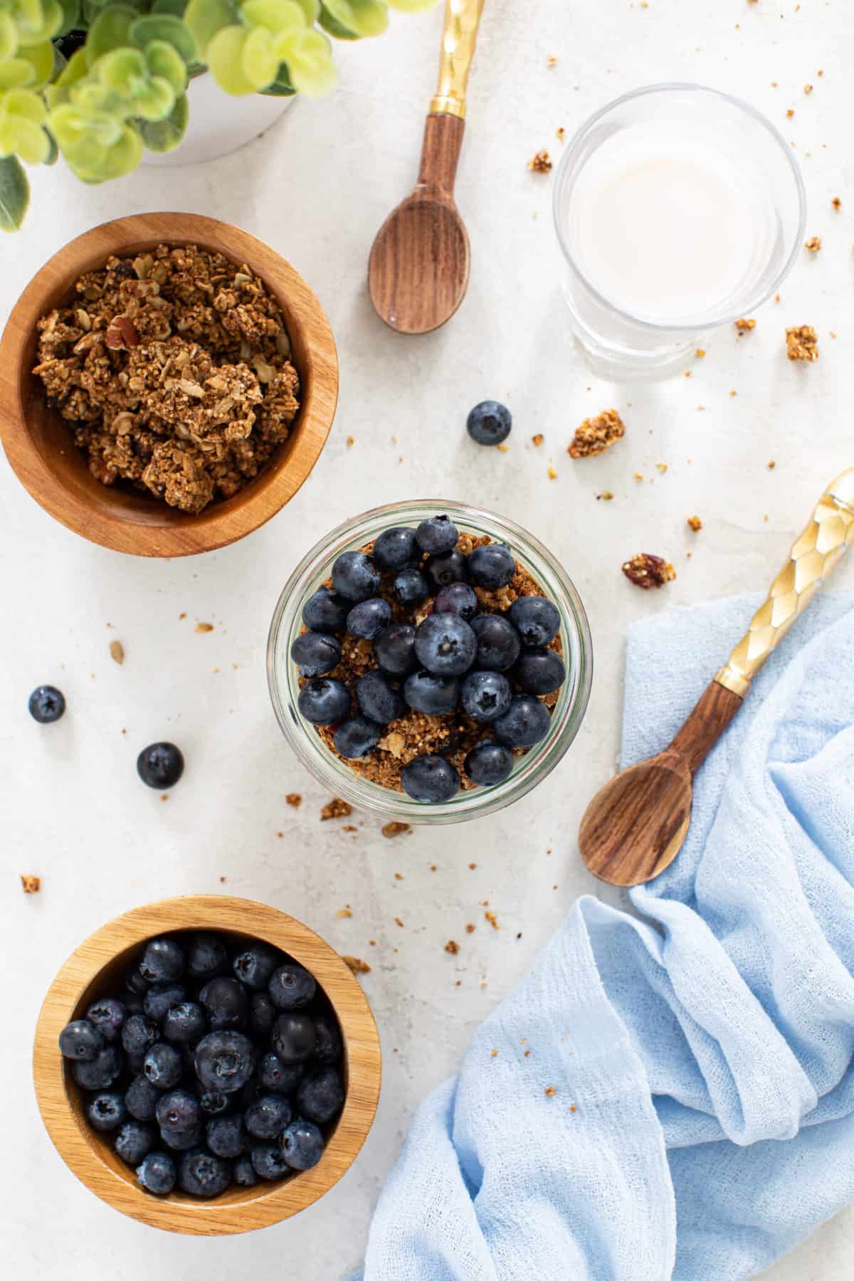 Overhead of breakfast with granola and blueberries on a white background. 