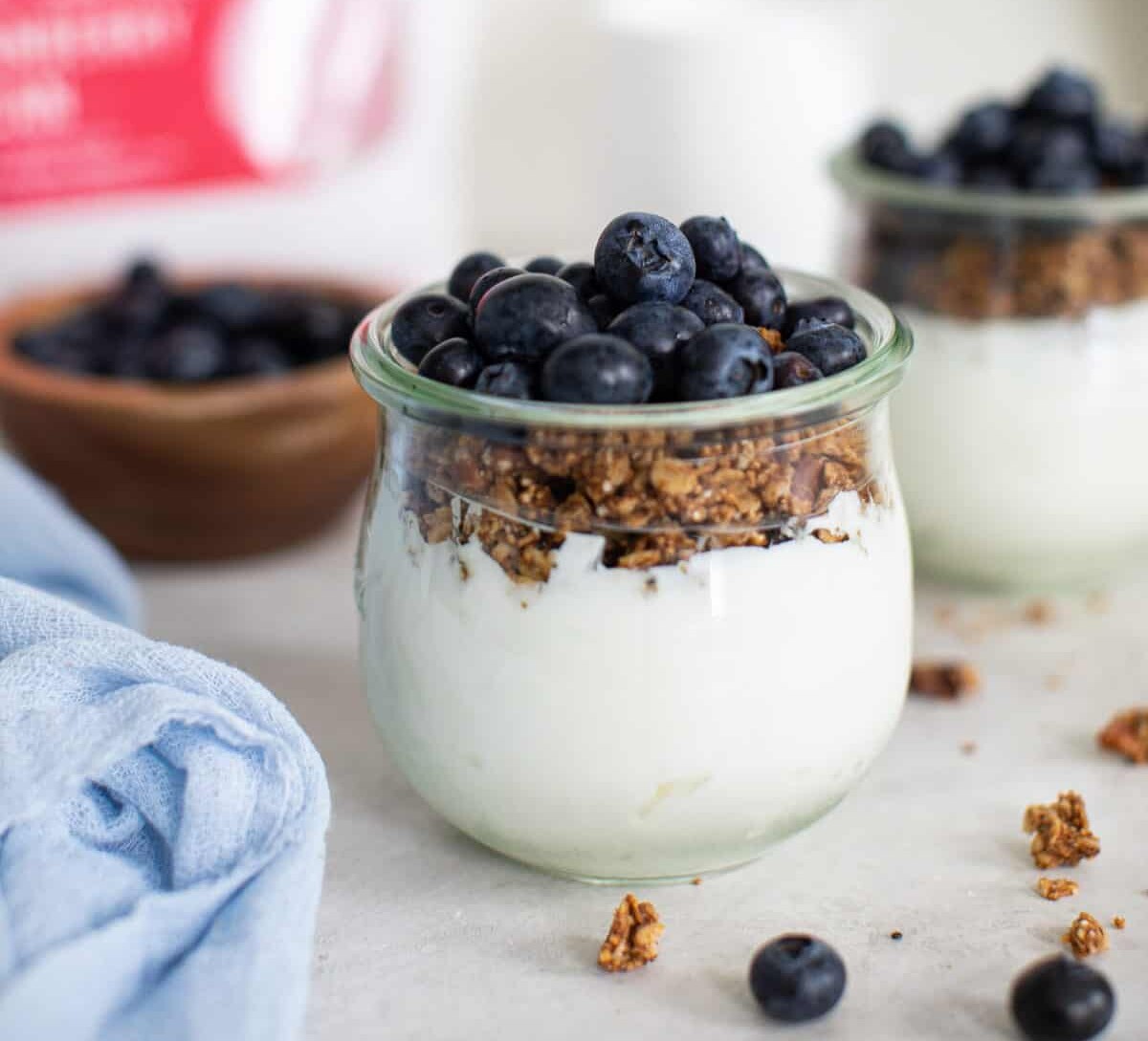 Close up on a clear glass jar with blueberry vegan parfaits.