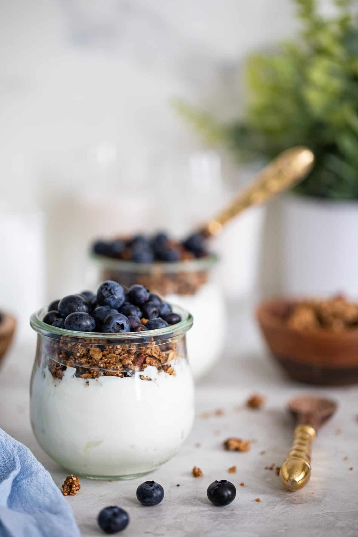 side view of two glass jars with vegan blueberry yogurt parfaits