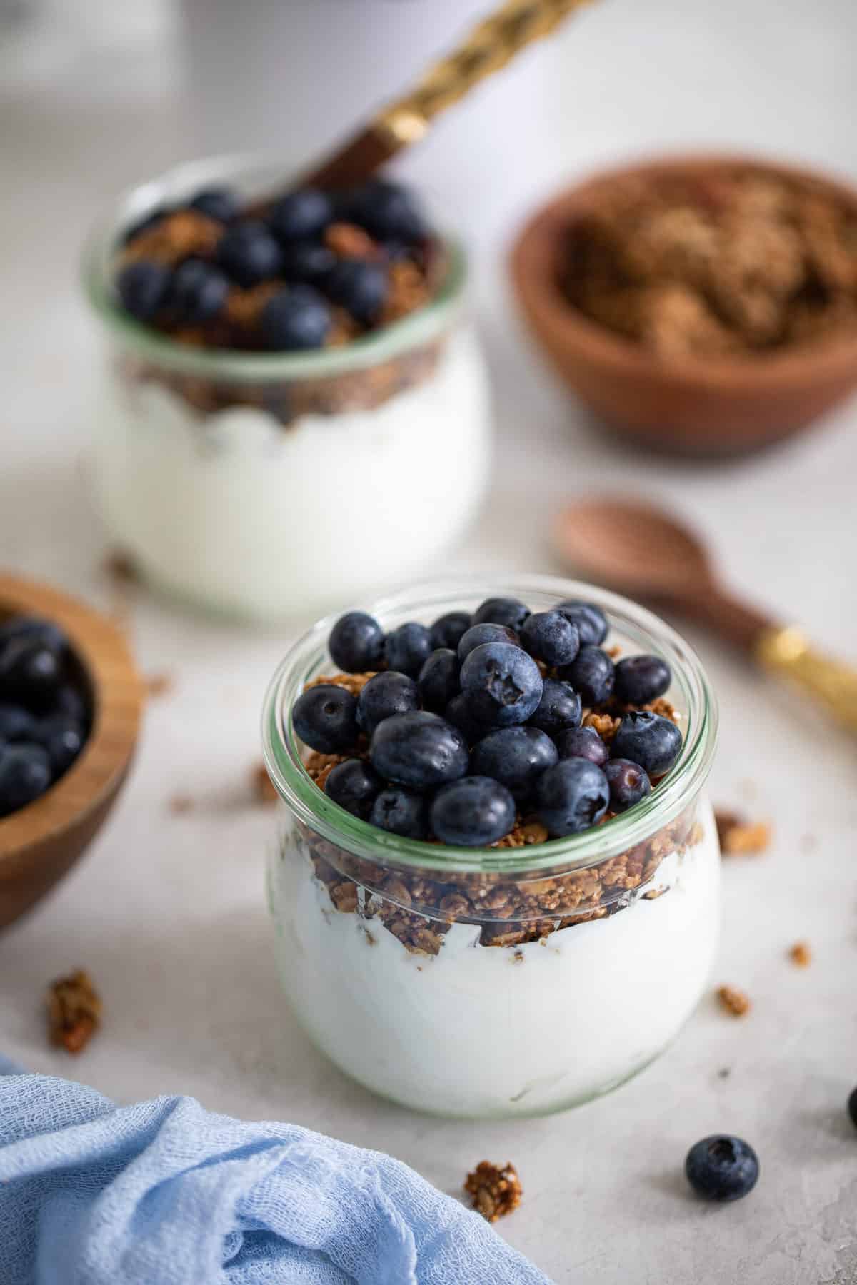 Blueberry Granola Yogurt Breakfast Parfaits on a white background with fresh berries and a blue napkin