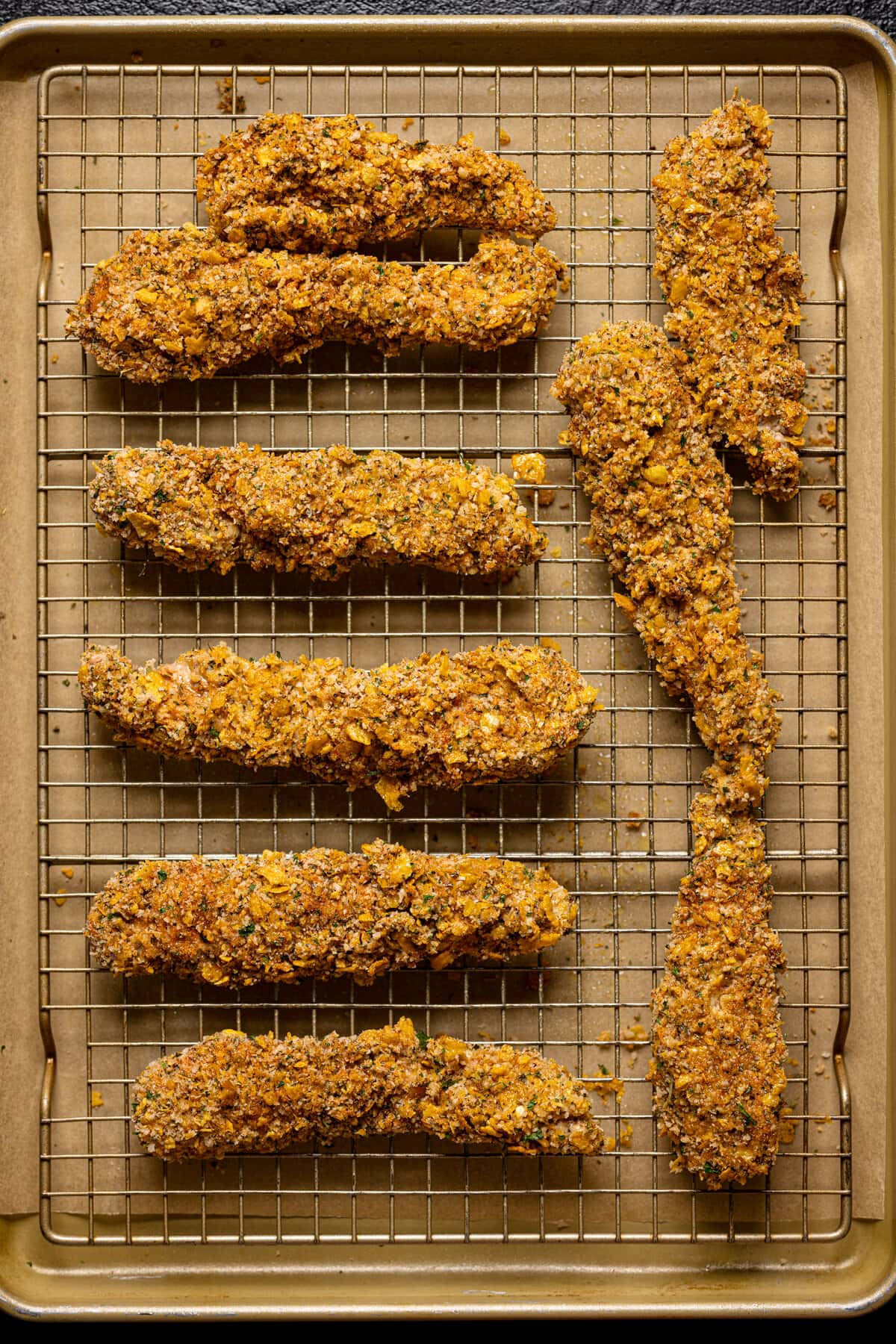 Uncooked Crispy Buffalo Chicken Tenders on a wire rack.