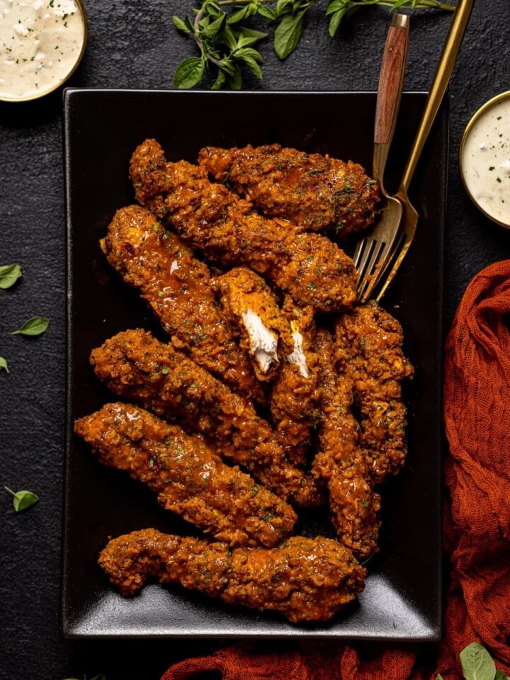 Crispy Buffalo Chicken Tenders and forks on a black plate.