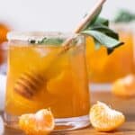 Citrus Honey Sage Drink in a small glass with a honey dipper.