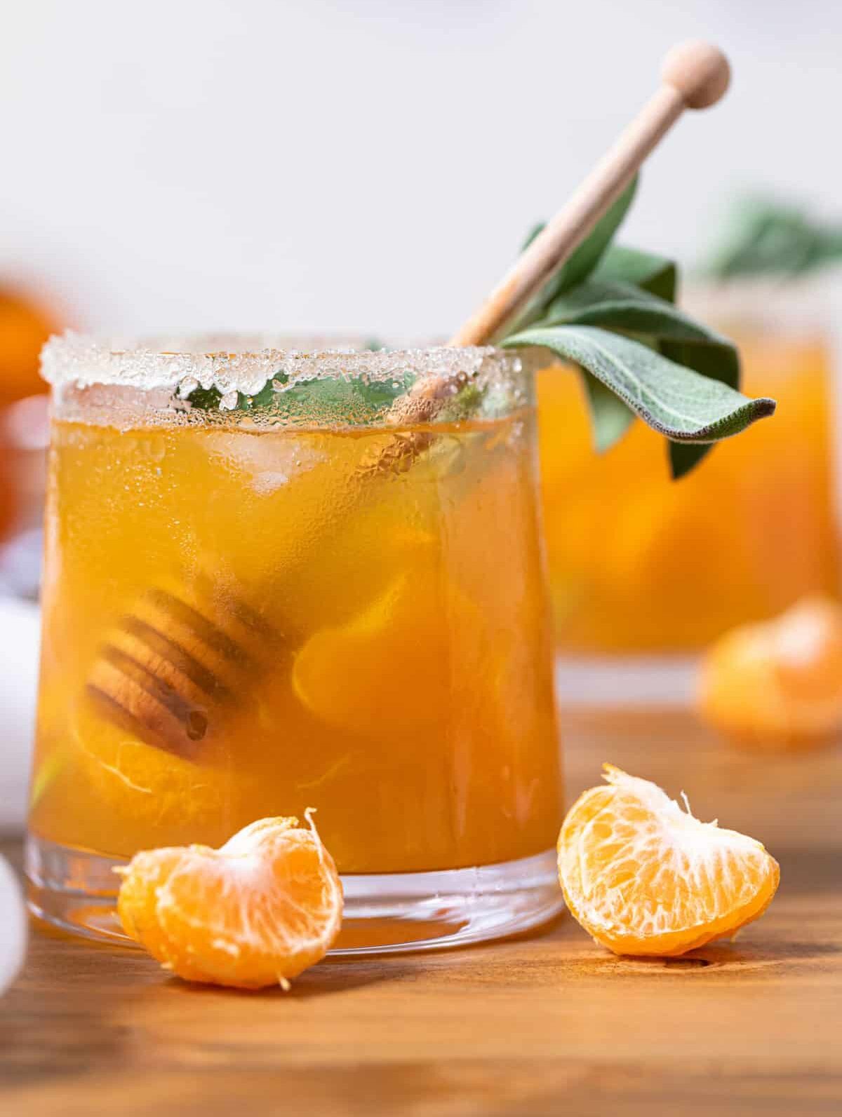 Citrus Honey Sage Drink in a small glass with a honey dipper
