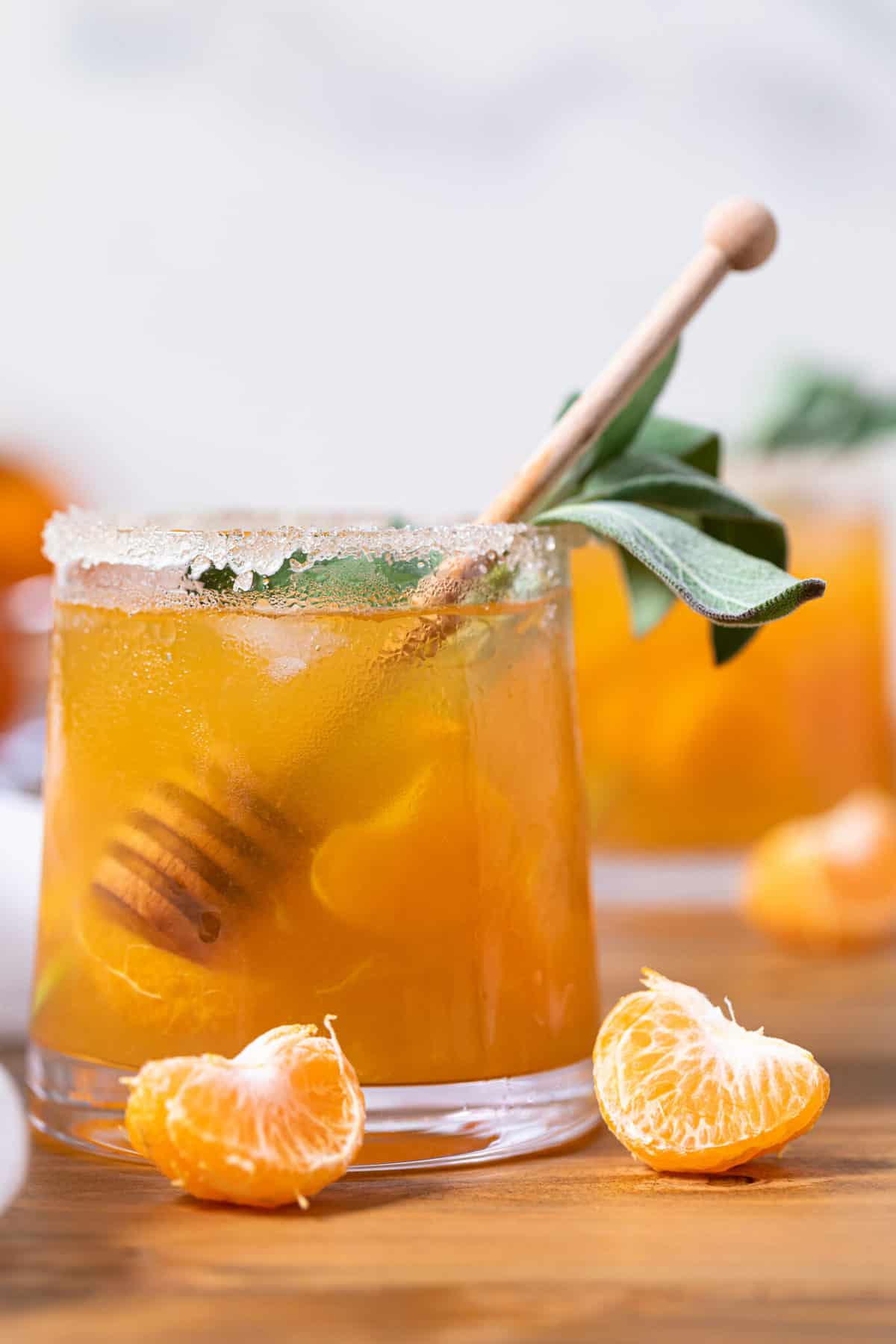 Citrus Honey Sage Drink in a small glass with a honey dipper