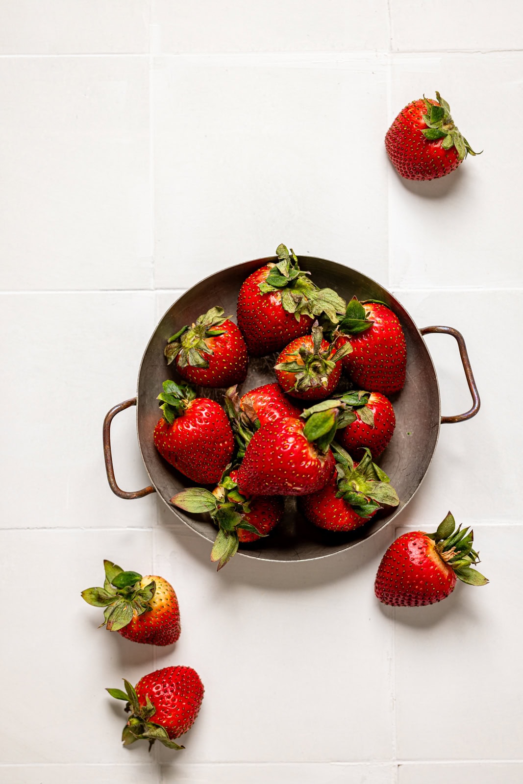 Strawberries on a white tile table.