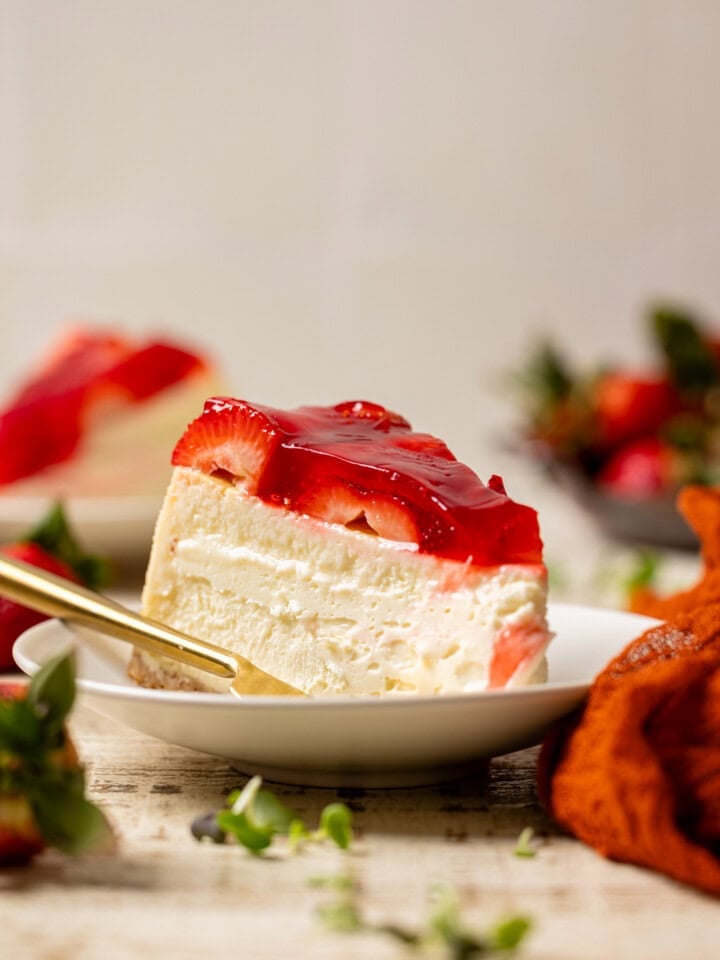 Slice of cheesecake with a fork and strawberries.
