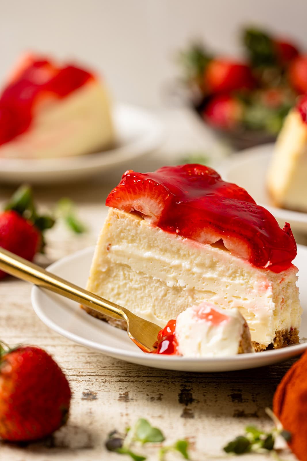 Up close shot of cheesecake slices with strawberries and a fork. 
