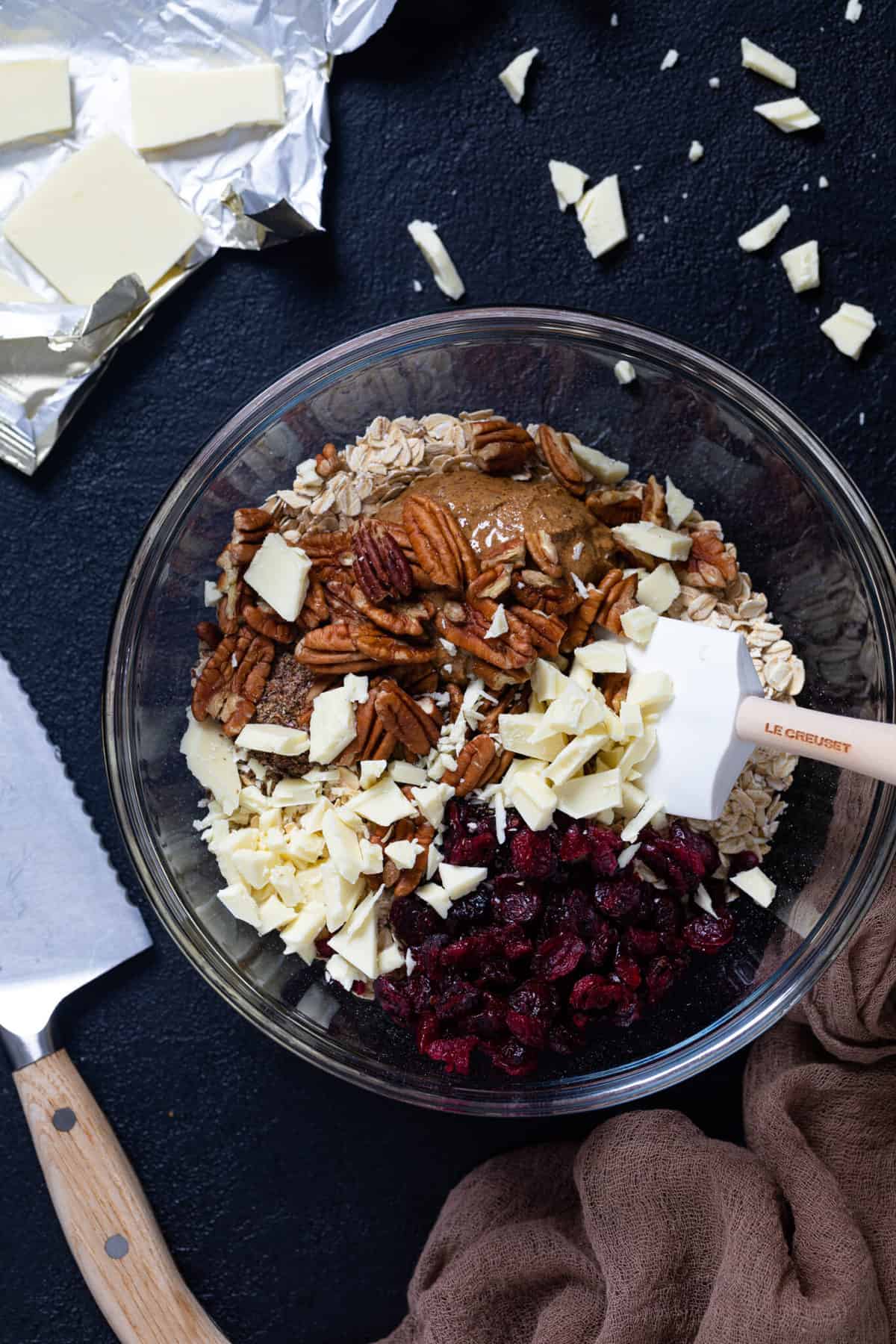 Overhead shot of the dough for White Chocolate Cranberry Energy Bites next to pieces of white chocolate on a countertop.