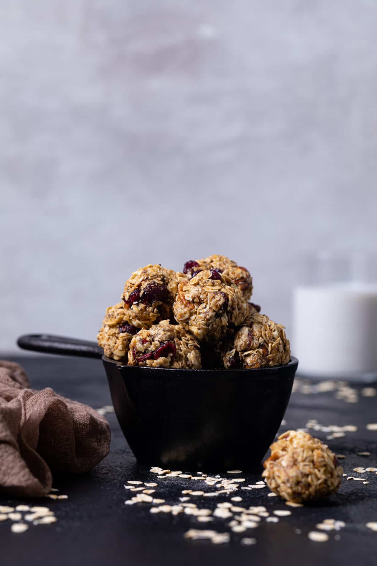 White Chocolate Cranberry Energy Bites in a black measuring cup on a black table.