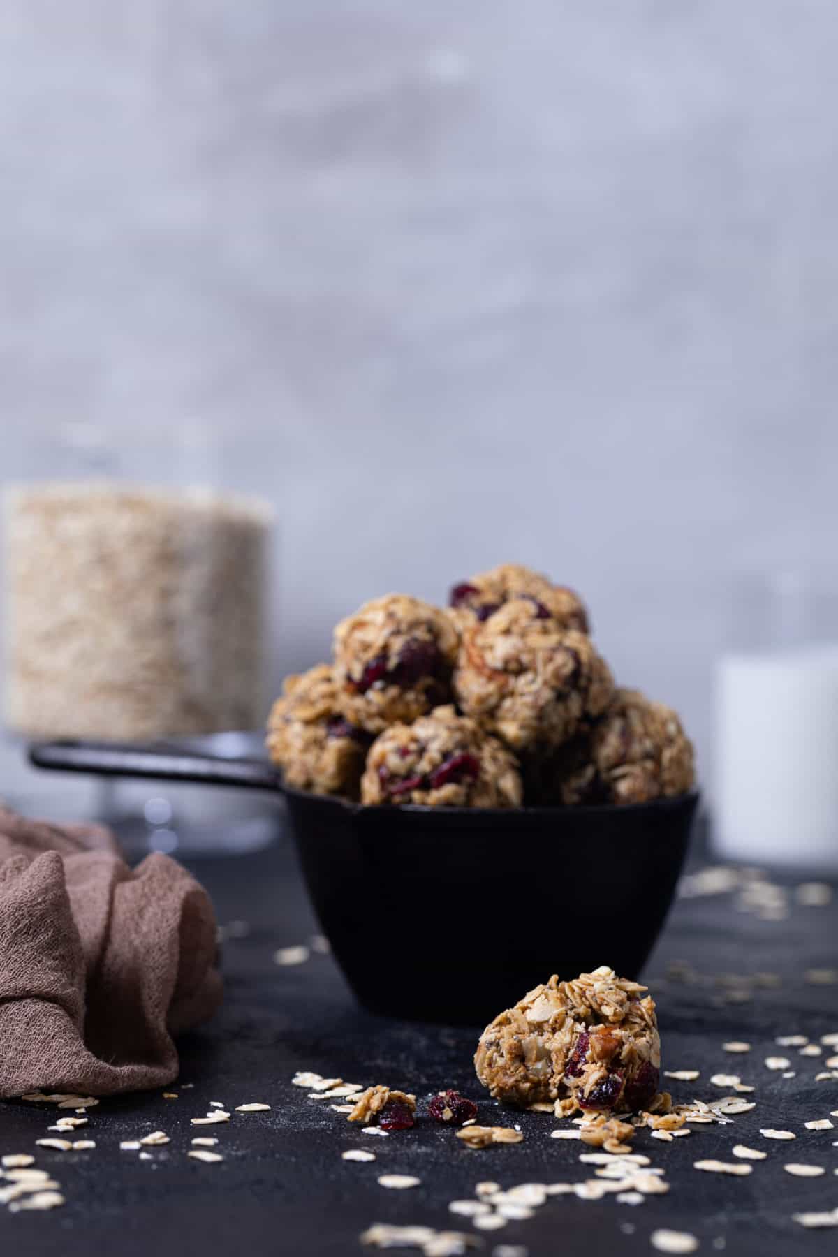 White Chocolate Cranberry Energy Bites in a measuring cup on a black table. 