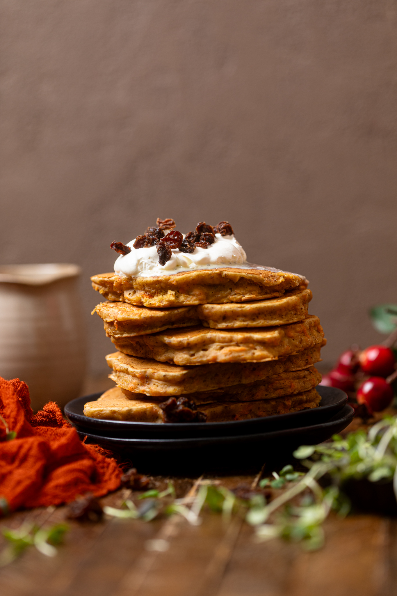 The Best Vegan Carrot Cake Pancakes stacked on black plates with a red napkin.