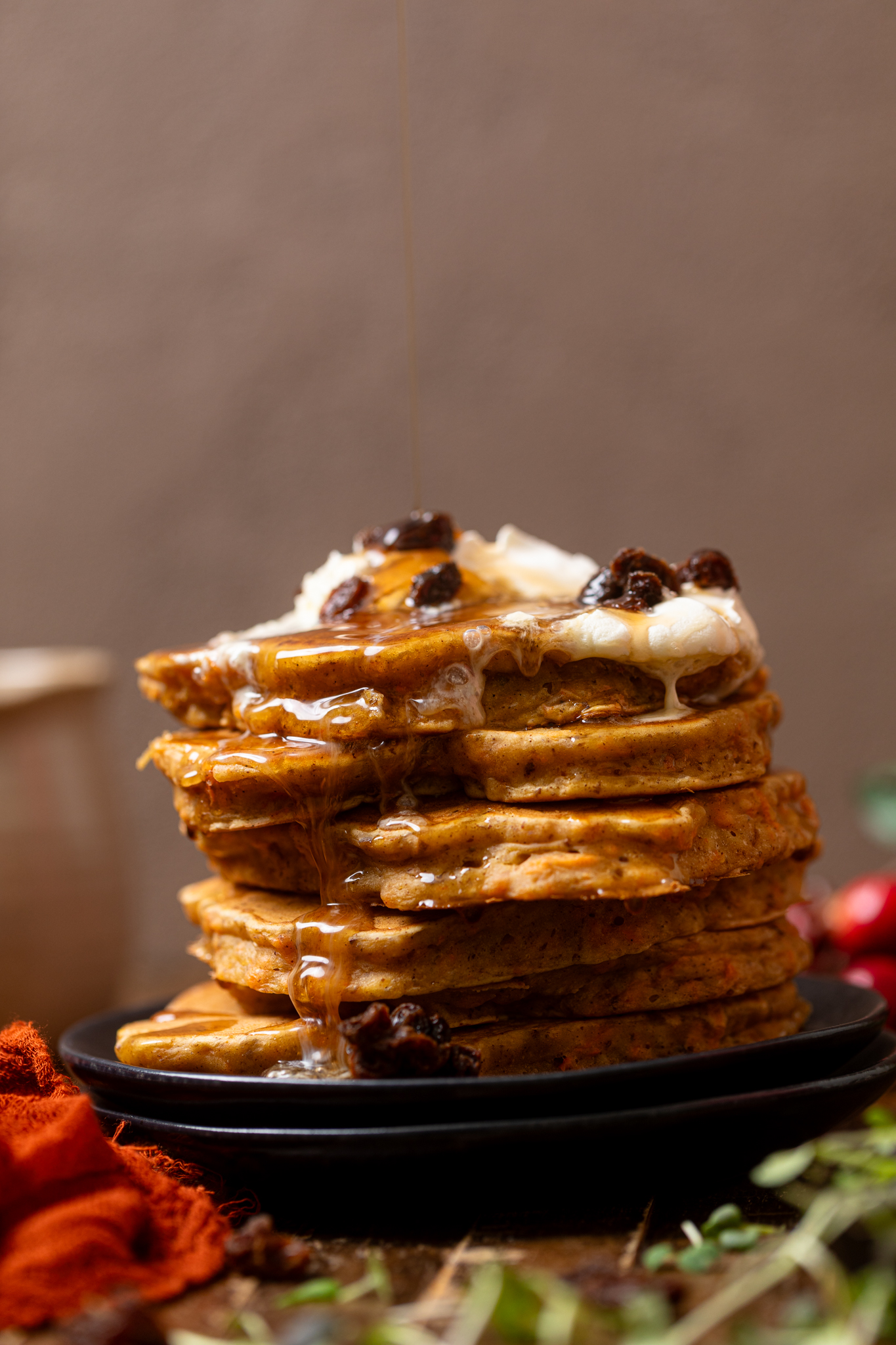The Best Vegan Carrot Cake Pancakes stacked with toppings and maple syrup.