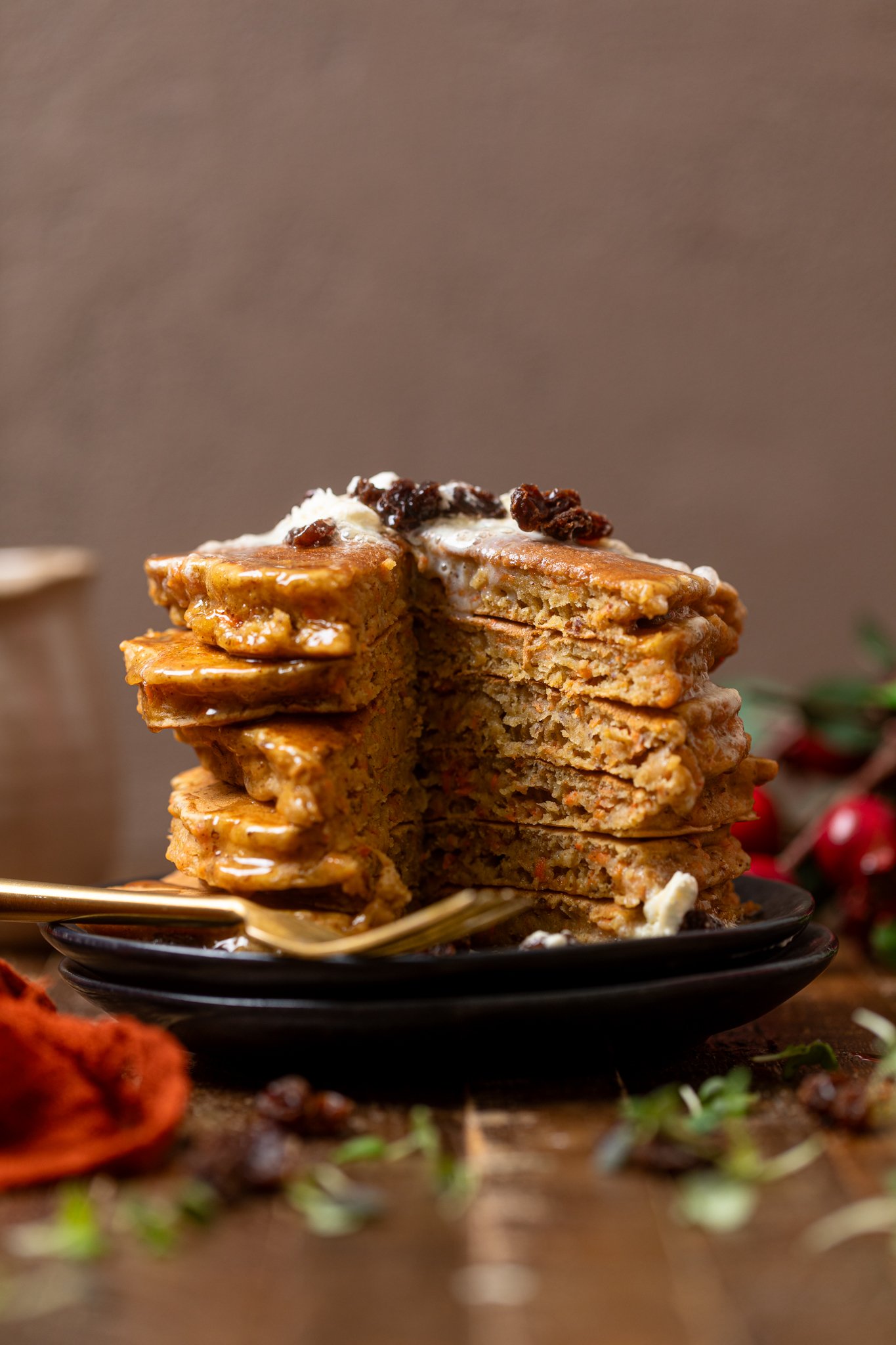 Vegan Carrot Cake Pancakes stacked on a black plate sliced to show insides.