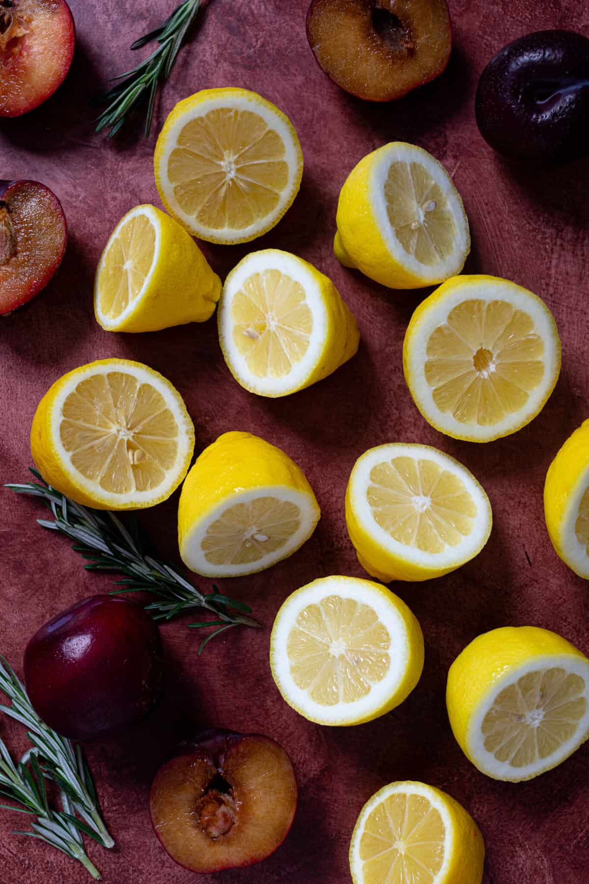 Sliced lemons and plums on a red background.