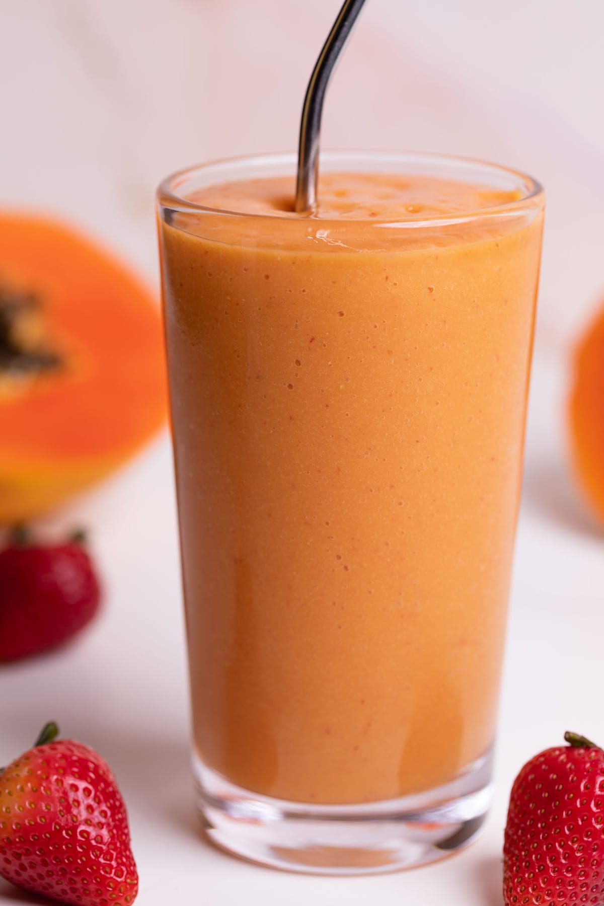 Strawberry Mango Papaya Smoothie in a glass with a metal straw.