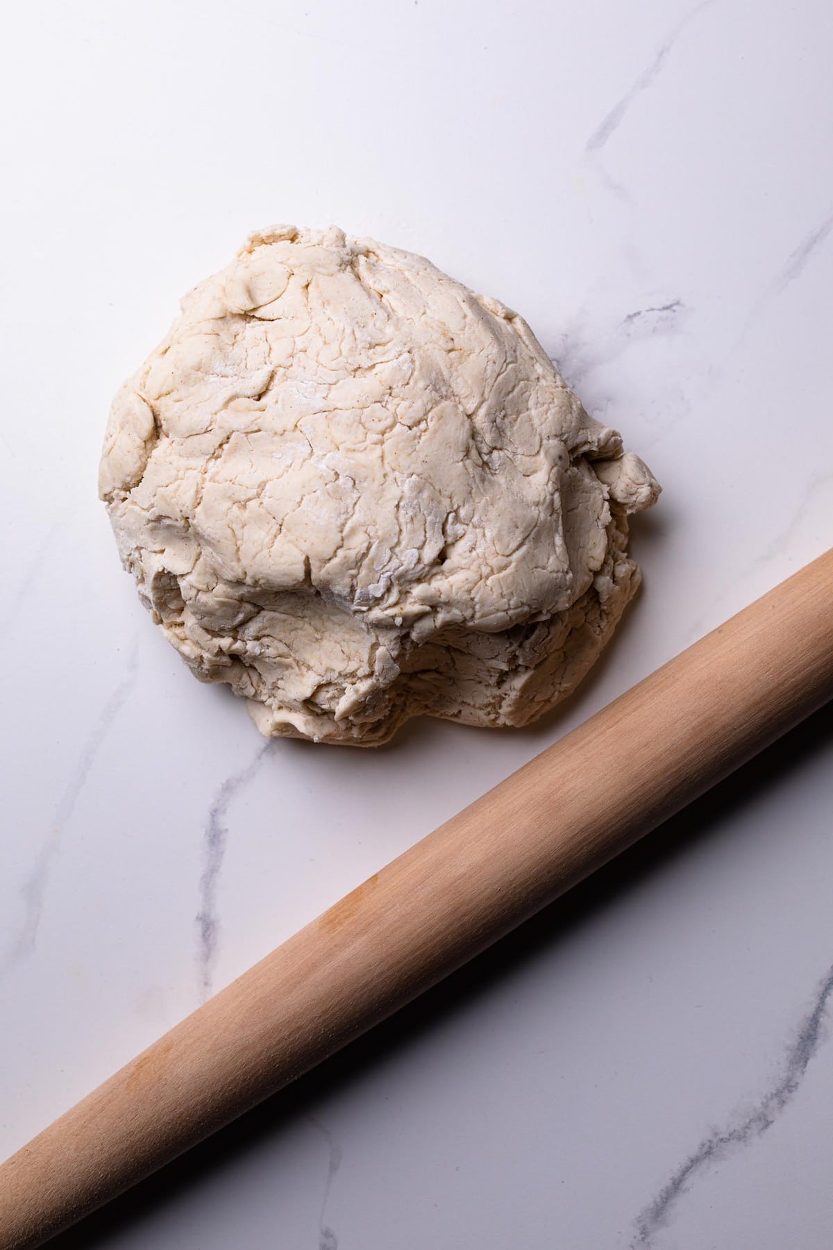 Homemade Gluten-Free Pizza Crust dough in a ball on a counter with a wooden rolling pin.