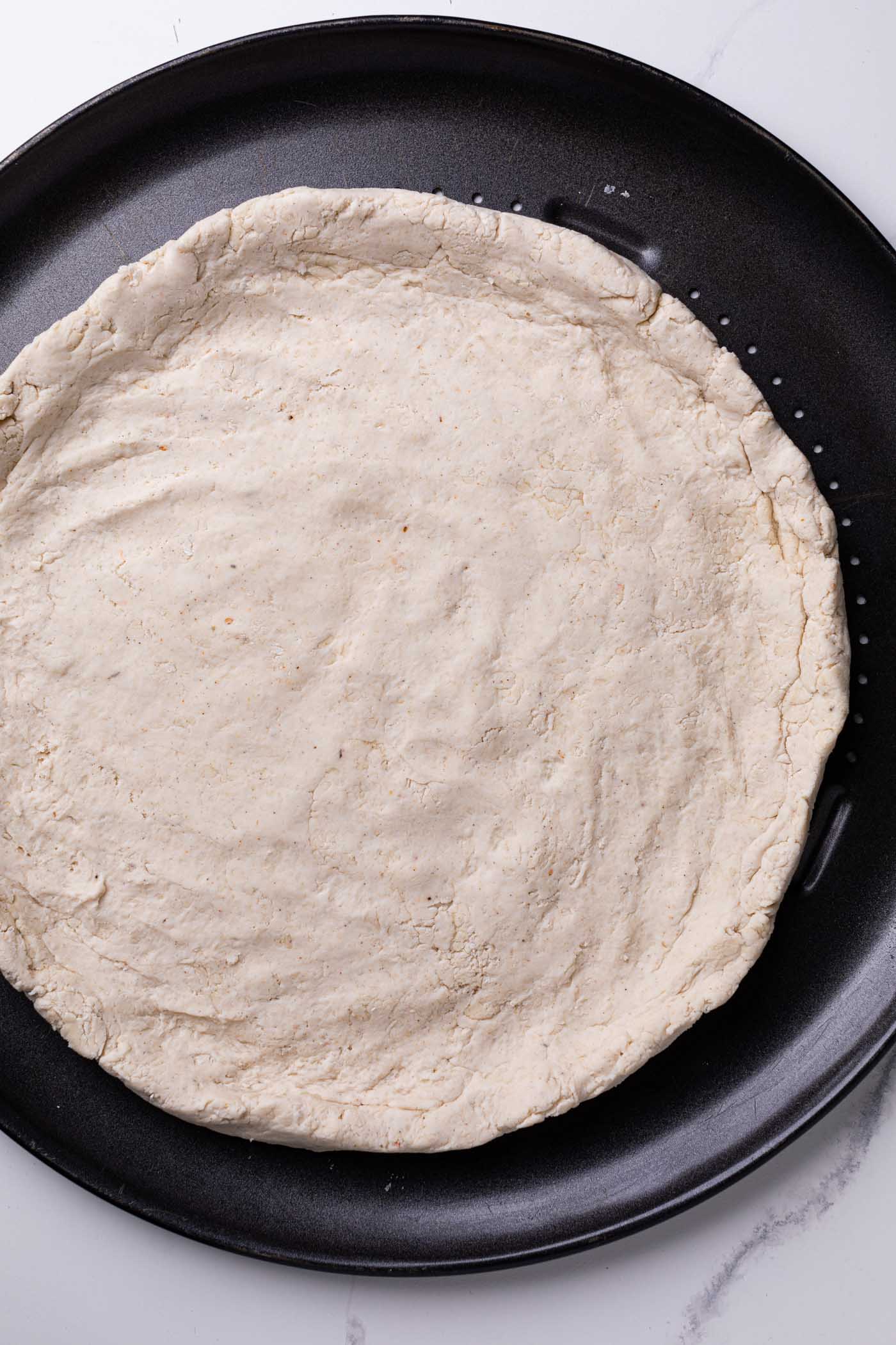 Homemade Gluten-Free Pizza Crust on a pizza pan, unbaked.