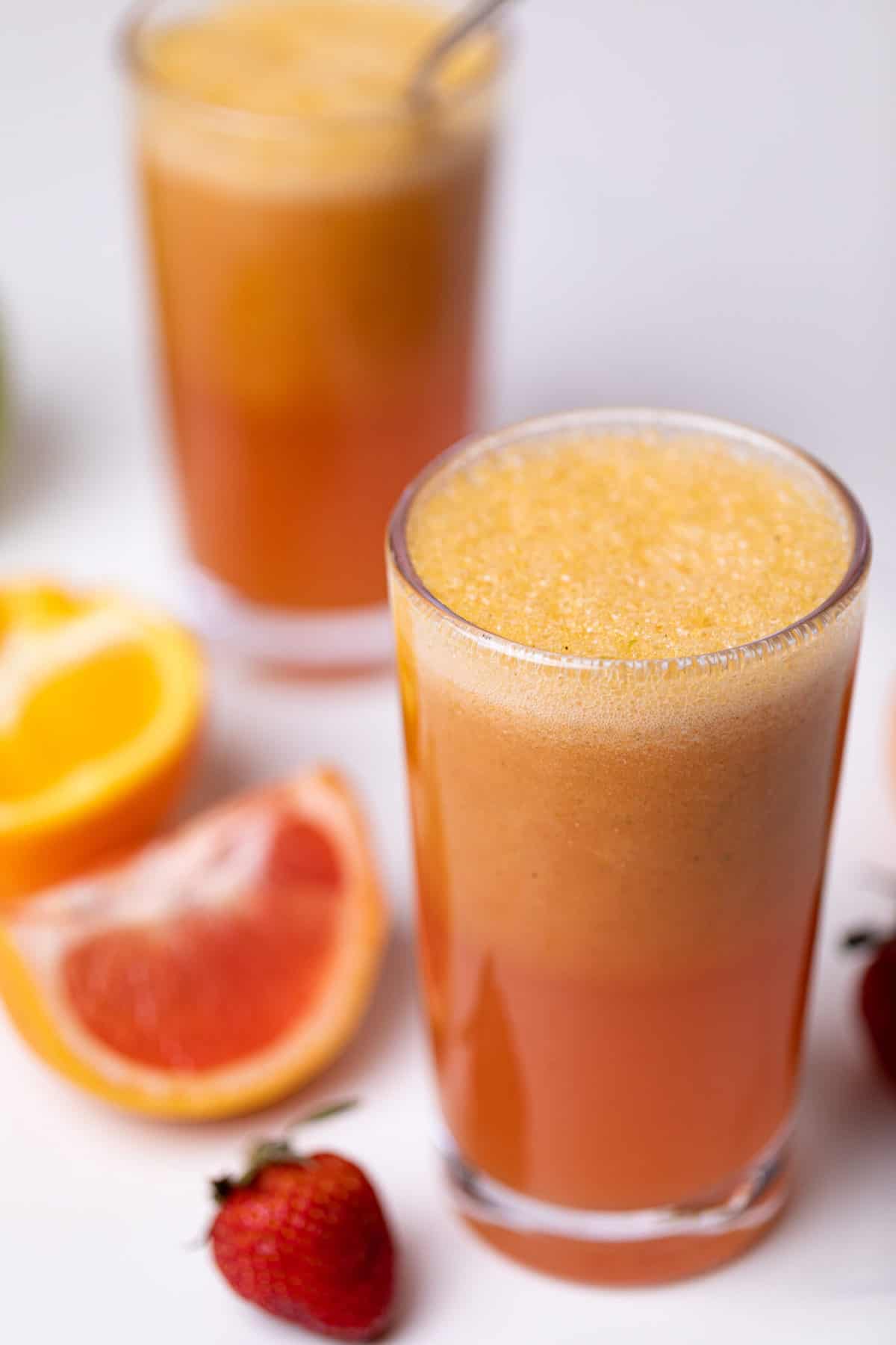 Apple Citrus Strawberry Juice in two glasses with fresh fruit.