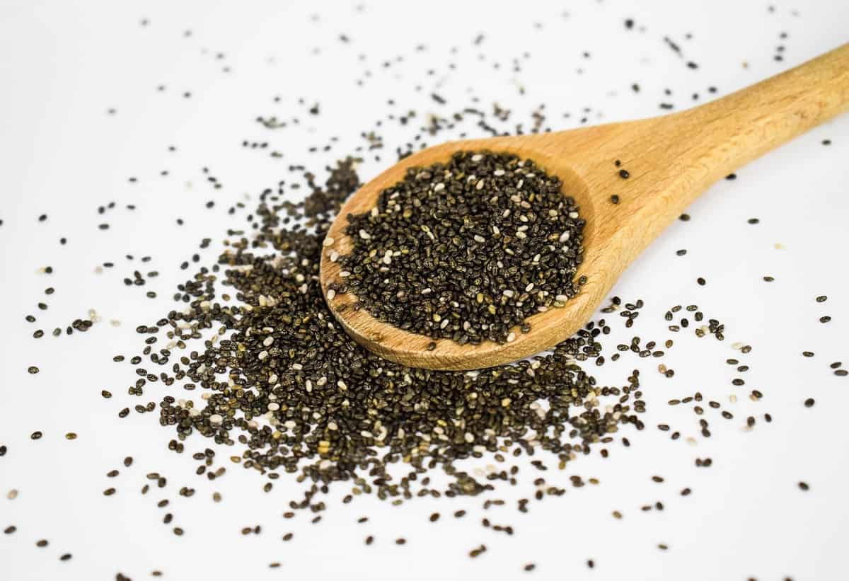 Wooden measuring spoon overflowing with chia seeds.