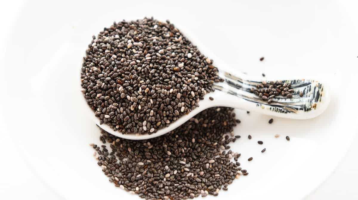 Metal measuring spoon overflowing with chia seeds.