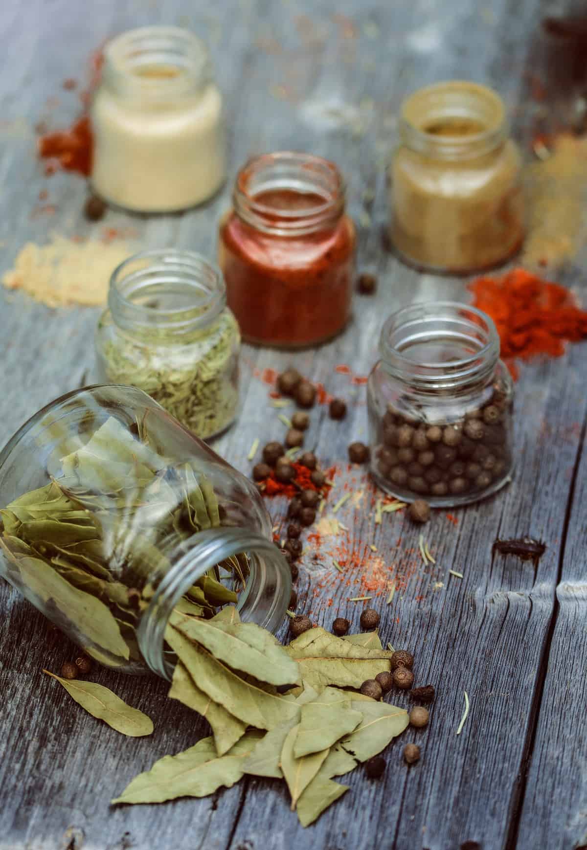 Jars of spices on a wooden table.