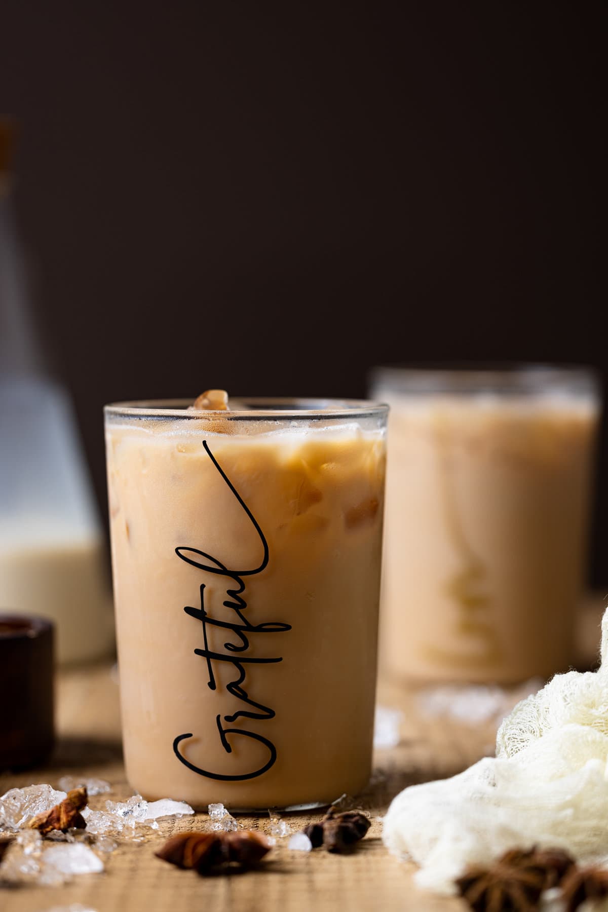 Iced Chai Tea Latte in a glass that reads \"Grateful\" on a wooden table