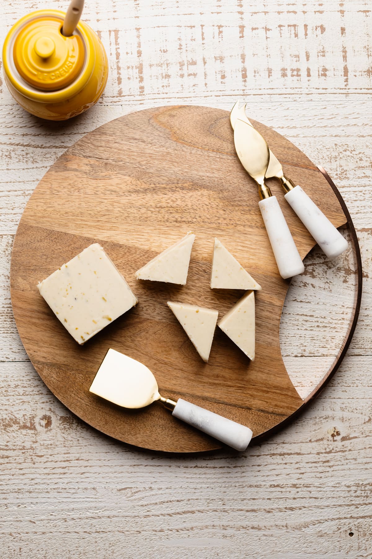 Vegan cheese and cheese slicers on a wooden board.