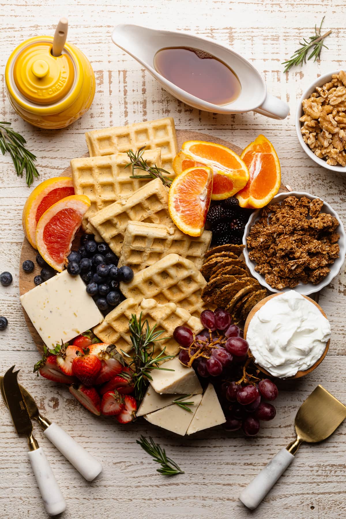 Wooden board stuffed with waffles, fruit, vegan cheese, and more.