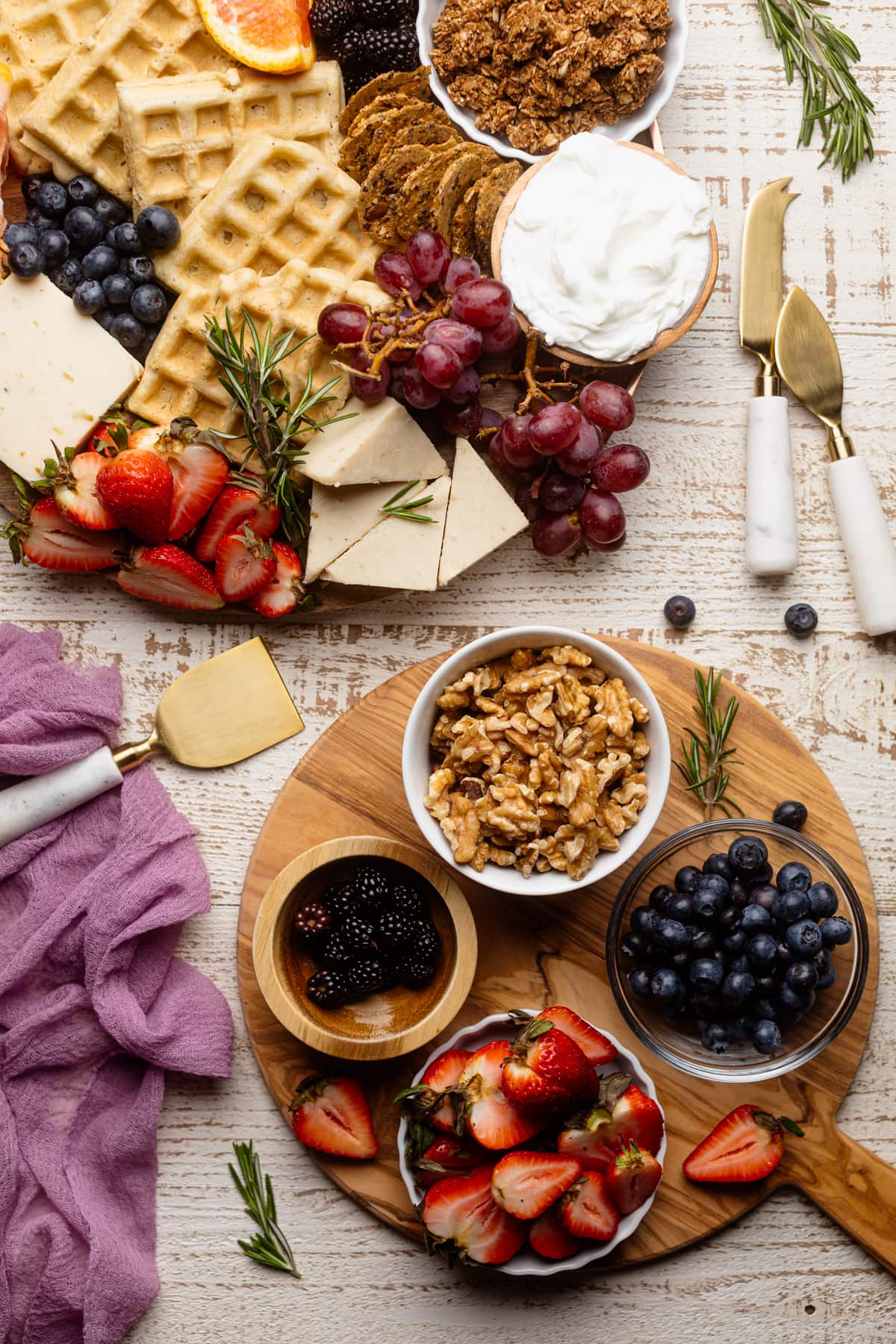 Two wooden boards set with fruits, nuts, and other ingredients.