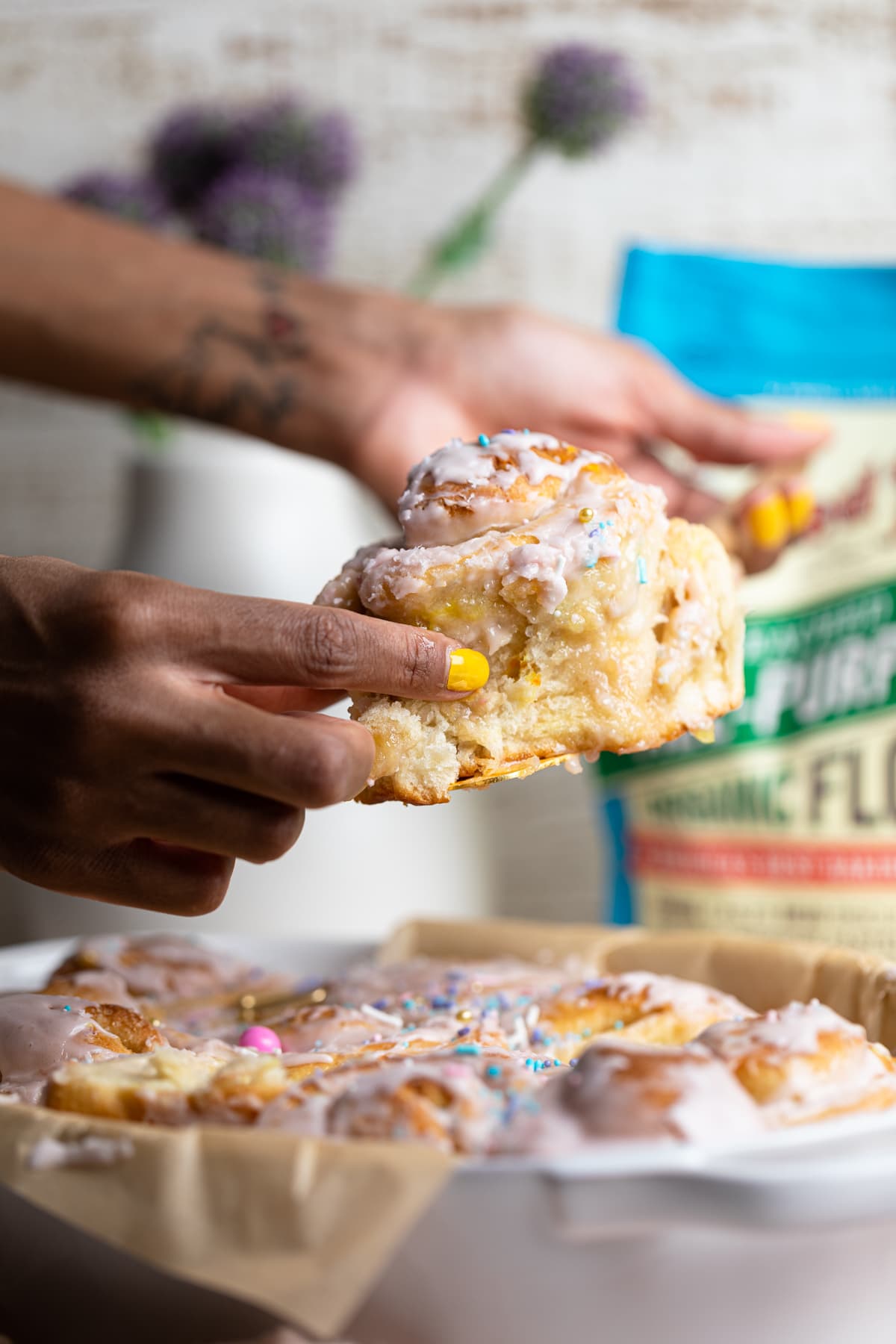 Hand grabbing a Vegan Funfetti Cinnamon Roll.