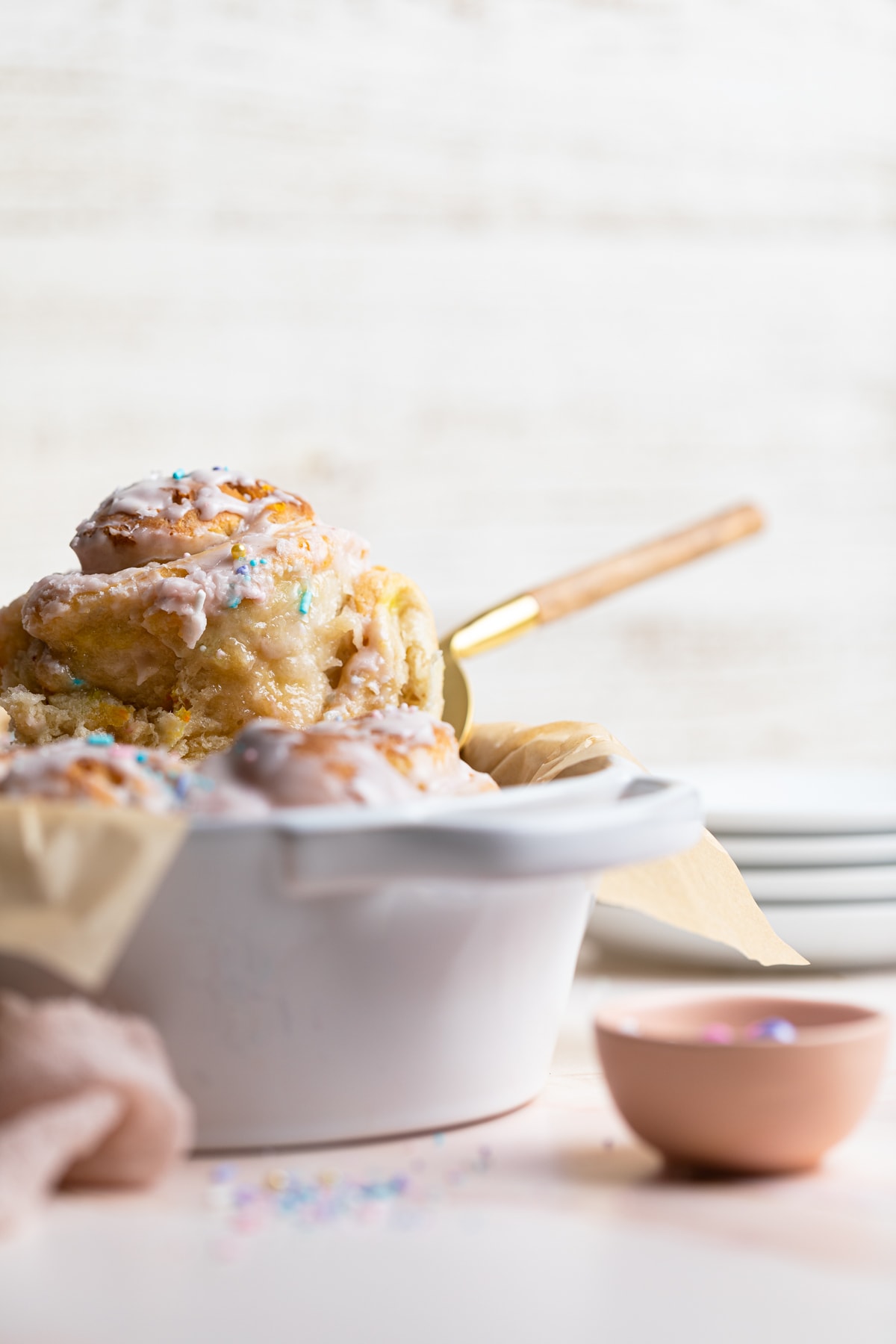 Vegan Funfetti Cinnamon Roll being removed from a white pan.