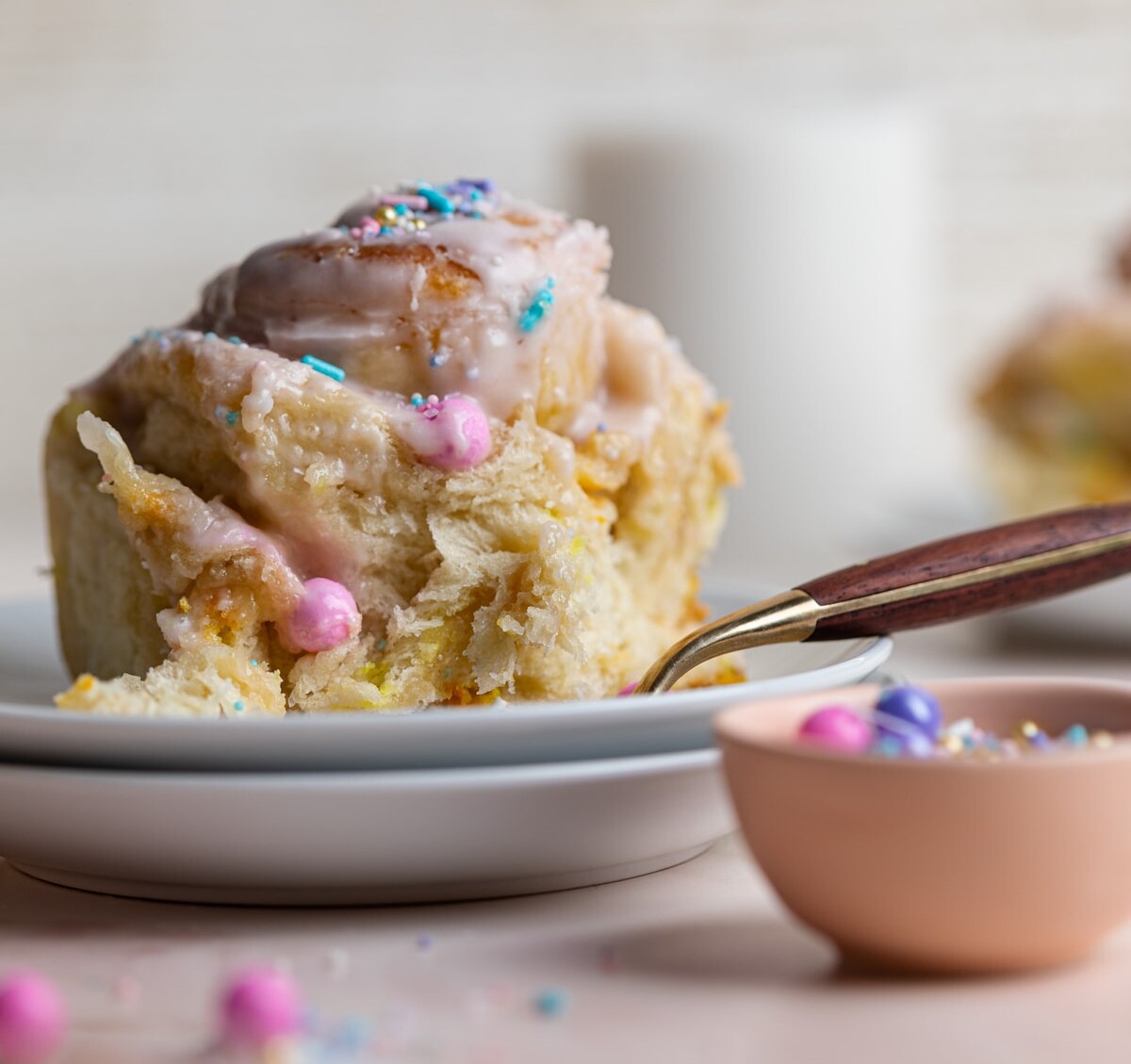 Small white plates with a Vegan Funfetti Cinnamon Roll.