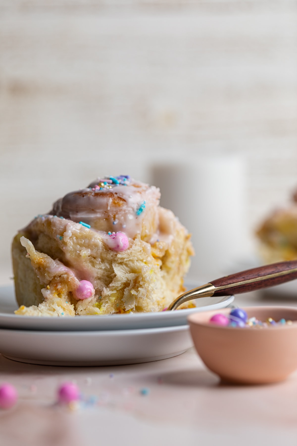 Small white plates with a Vegan Funfetti Cinnamon Roll.