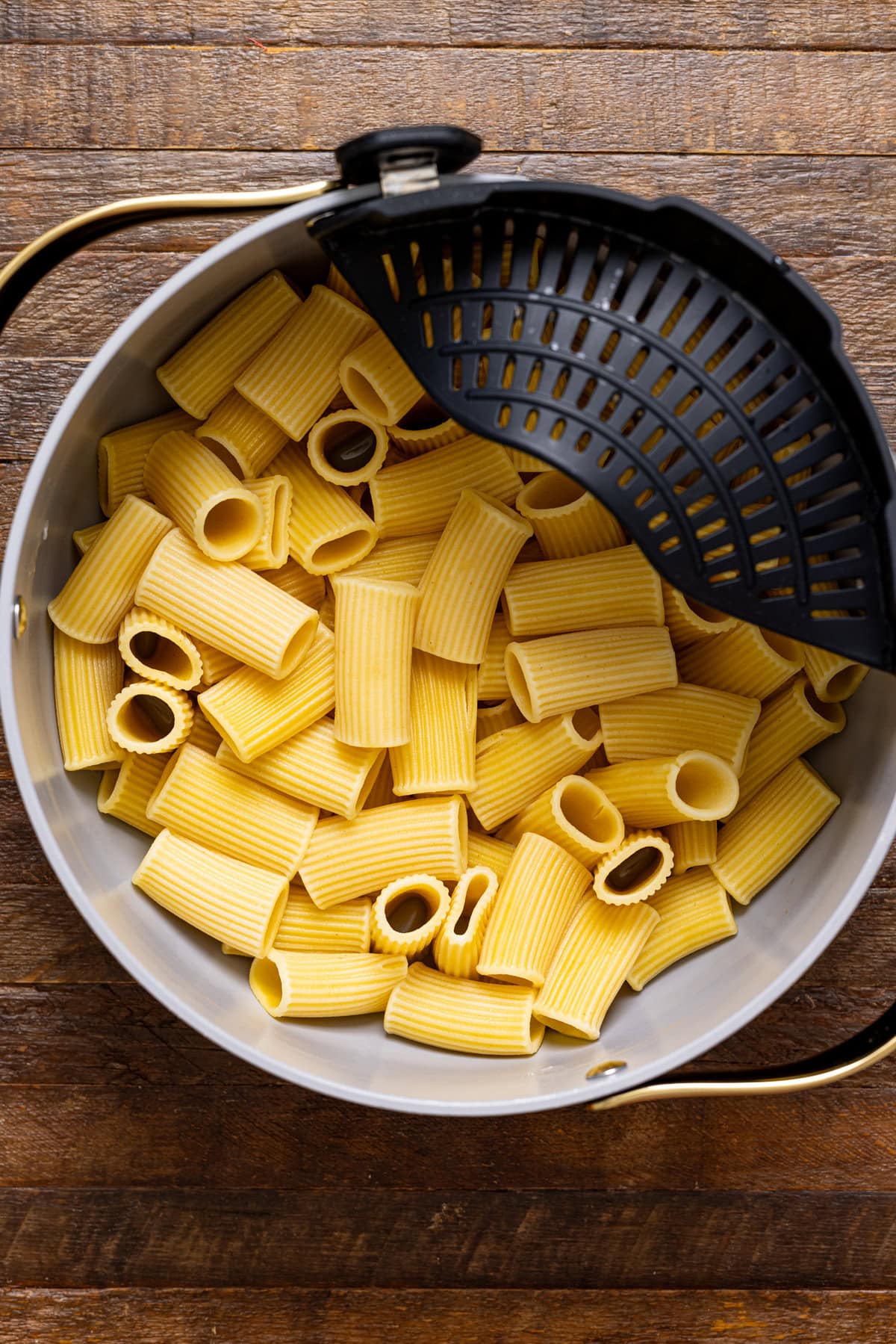 Cooked pasta in a pot on a brown wood table.