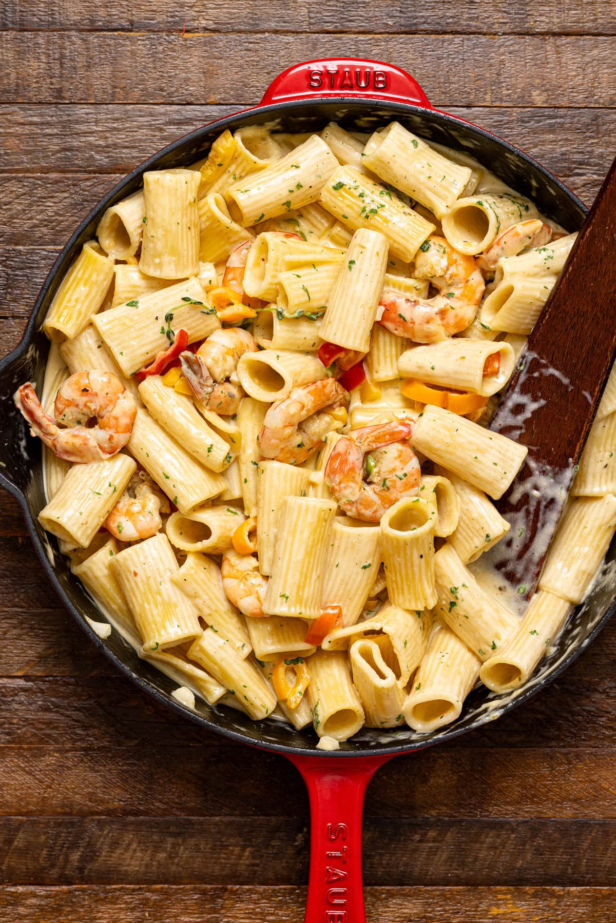 Rasta Pasta in a red skillet with a wooden spoon.