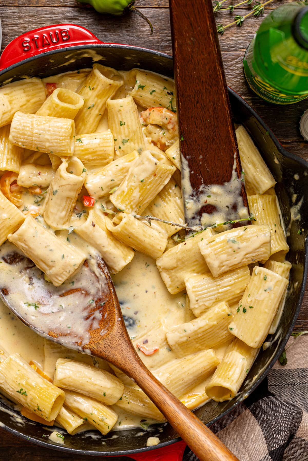 Shrimp rasta pasta in a skillet scooped with wooden spoons.