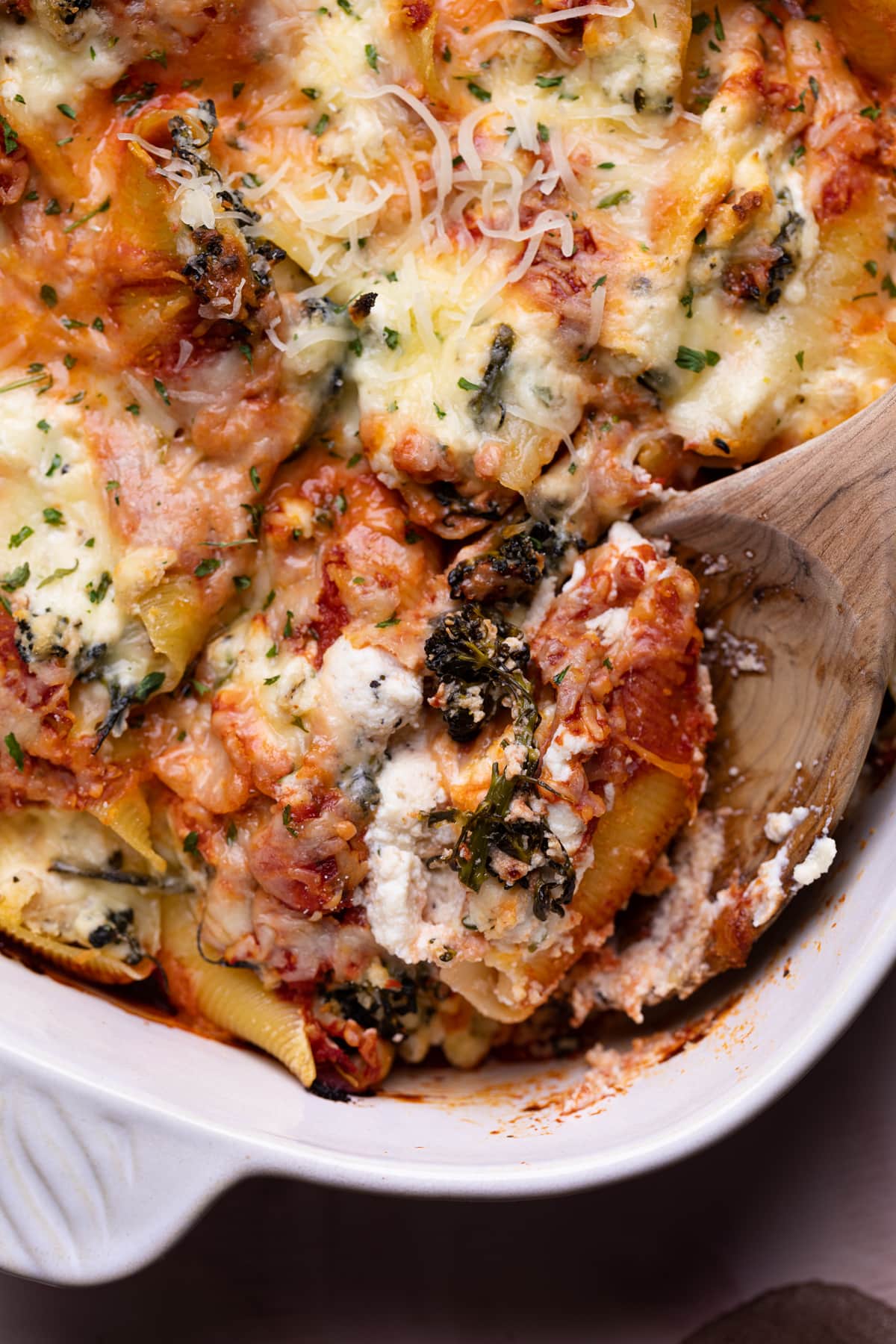 Scoop of Roasted Broccolini and Chicken Ricotta Stuffed Shells on a wooden spoon.