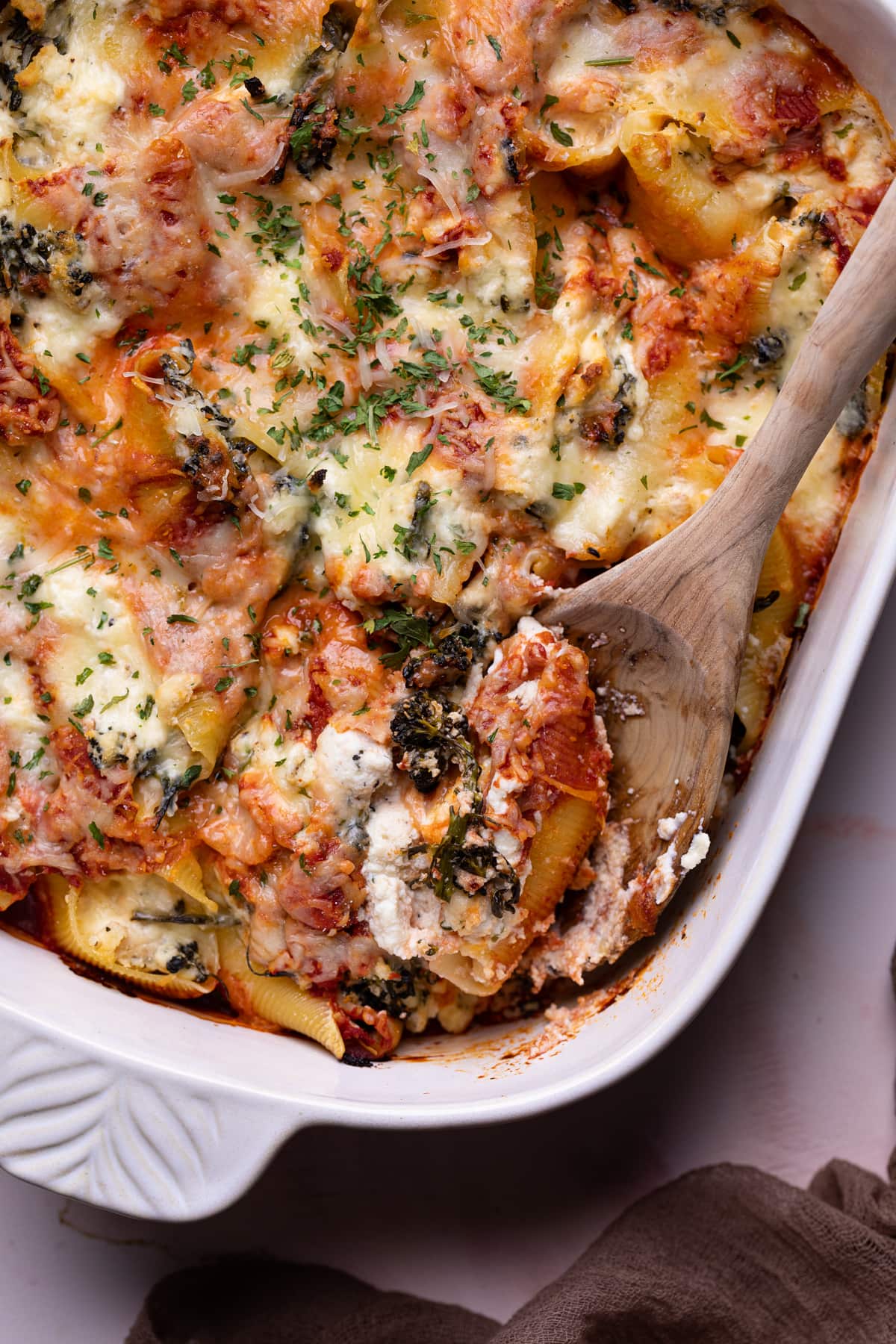 Roasted Broccolini and Chicken Ricotta Stuffed Shells with a wooden spoon.